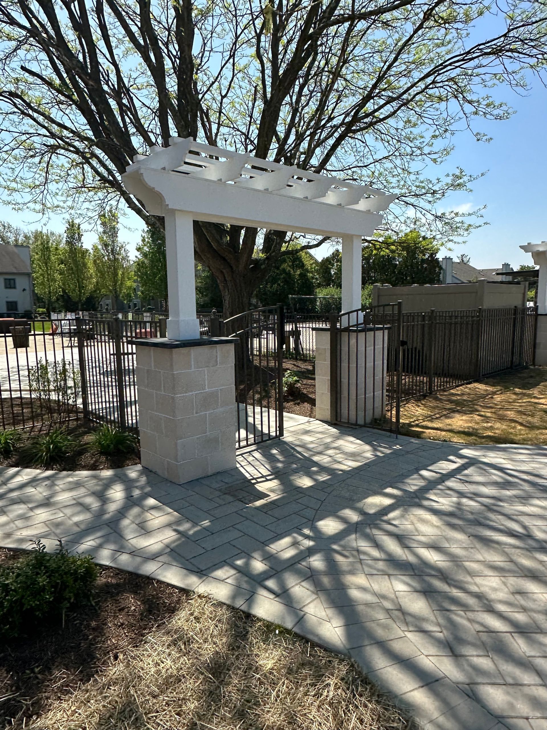 A white pergola is sitting under a tree in a park.