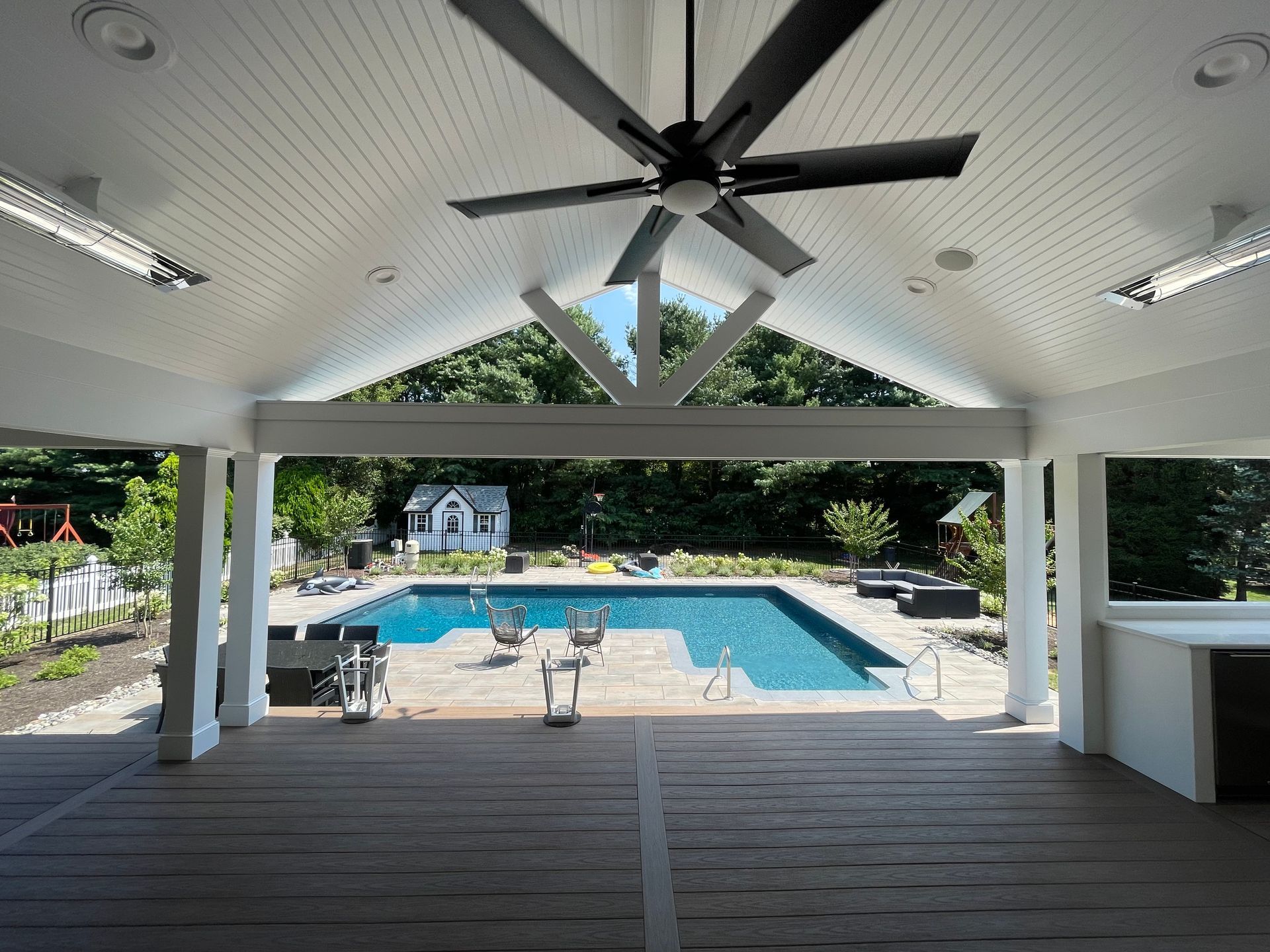 A ceiling fan is hanging from the ceiling above a swimming pool.