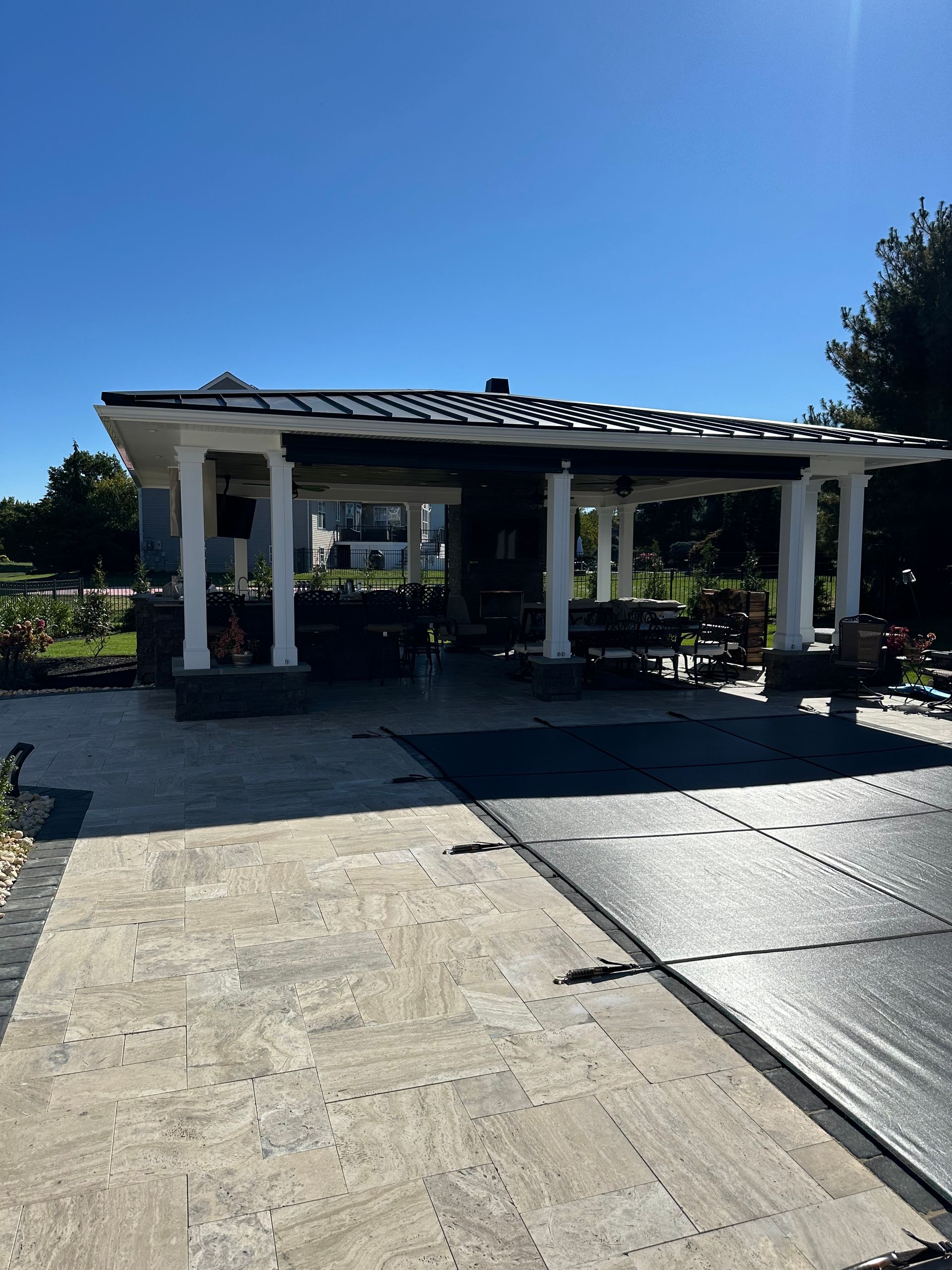 A white house with a black roof is sitting on top of a concrete driveway.