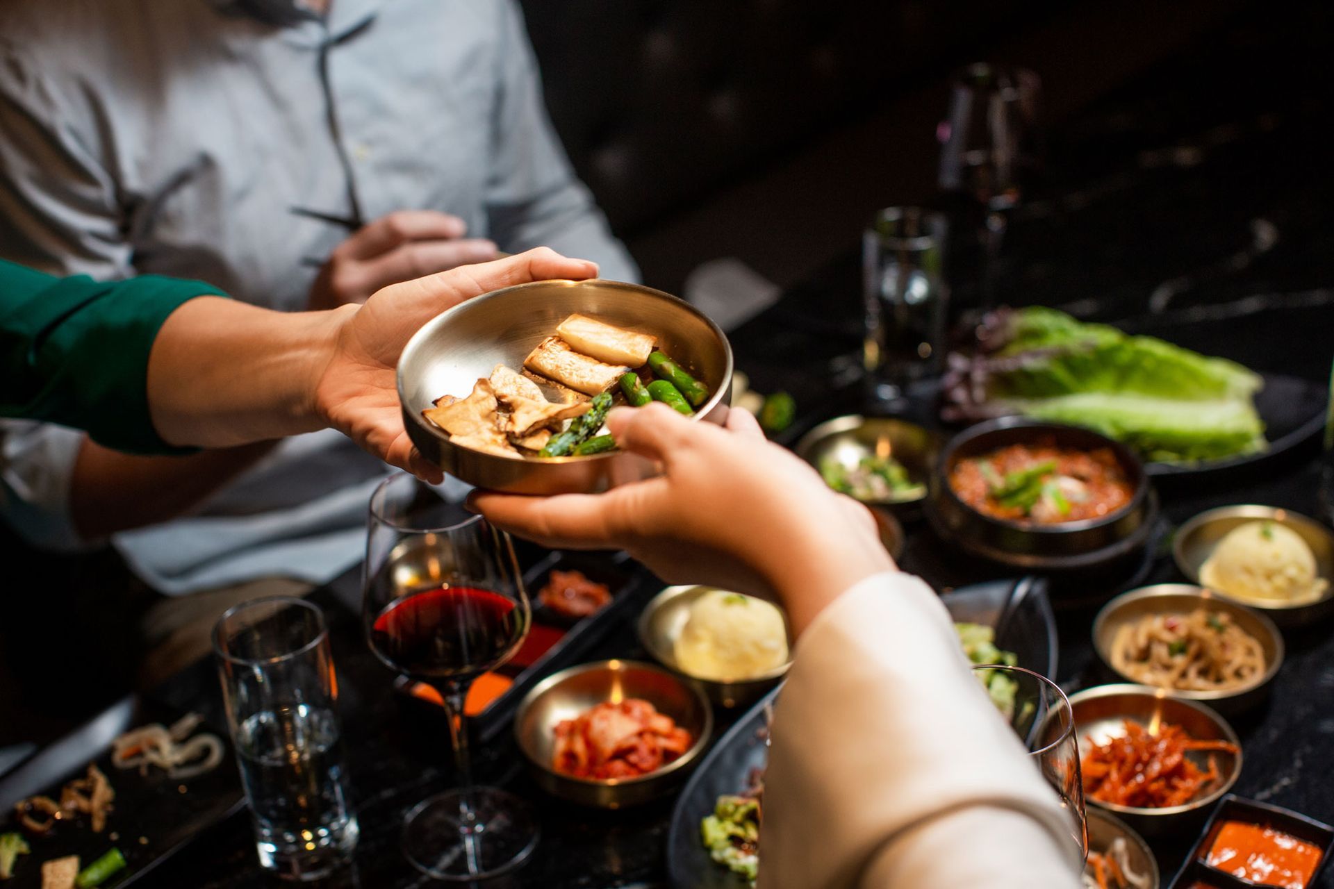 A woman is giving a bowl of food to a man at a table.