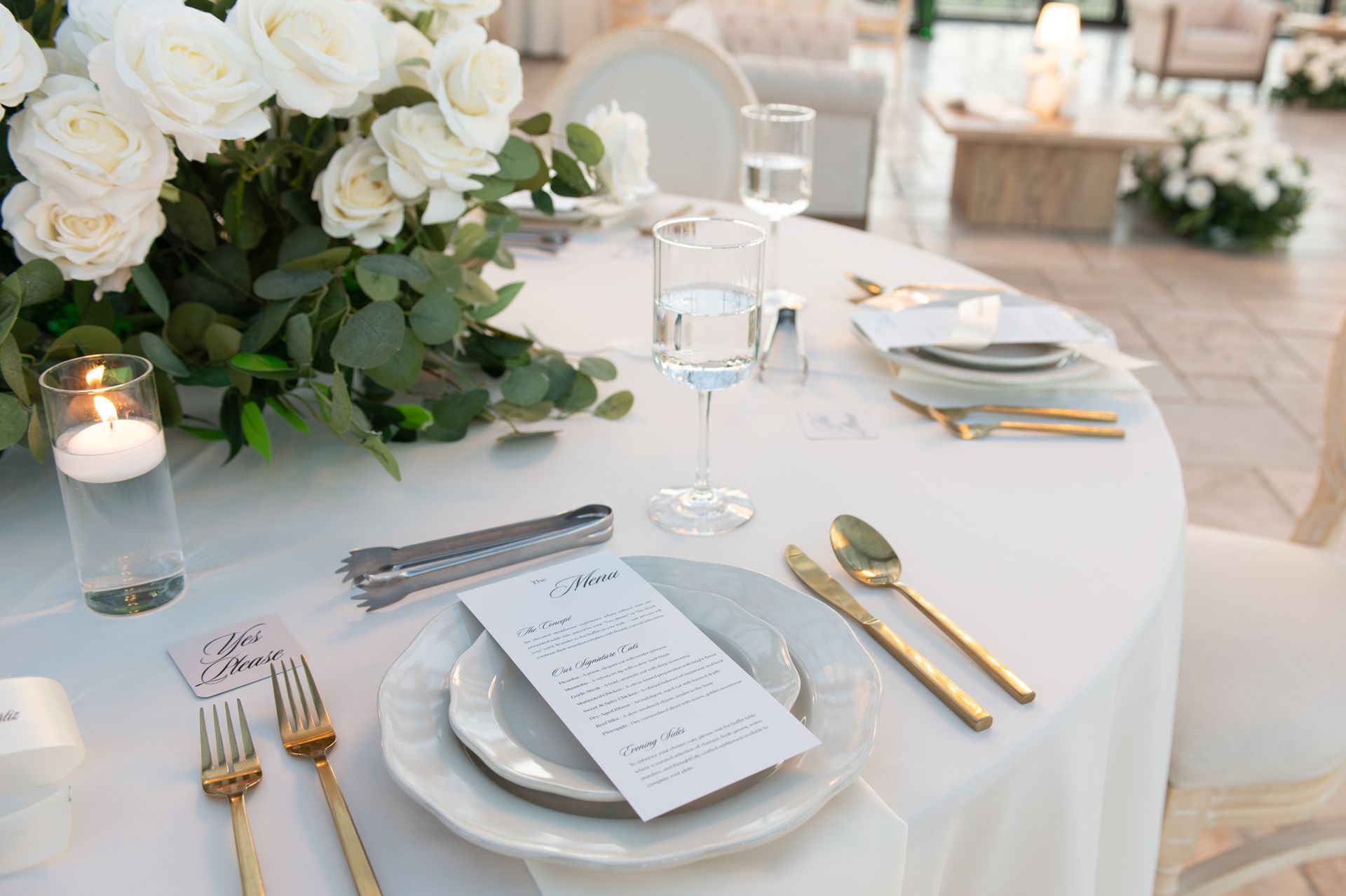 Elegant banquet table with white flowers, candles, and gold-accented place settings