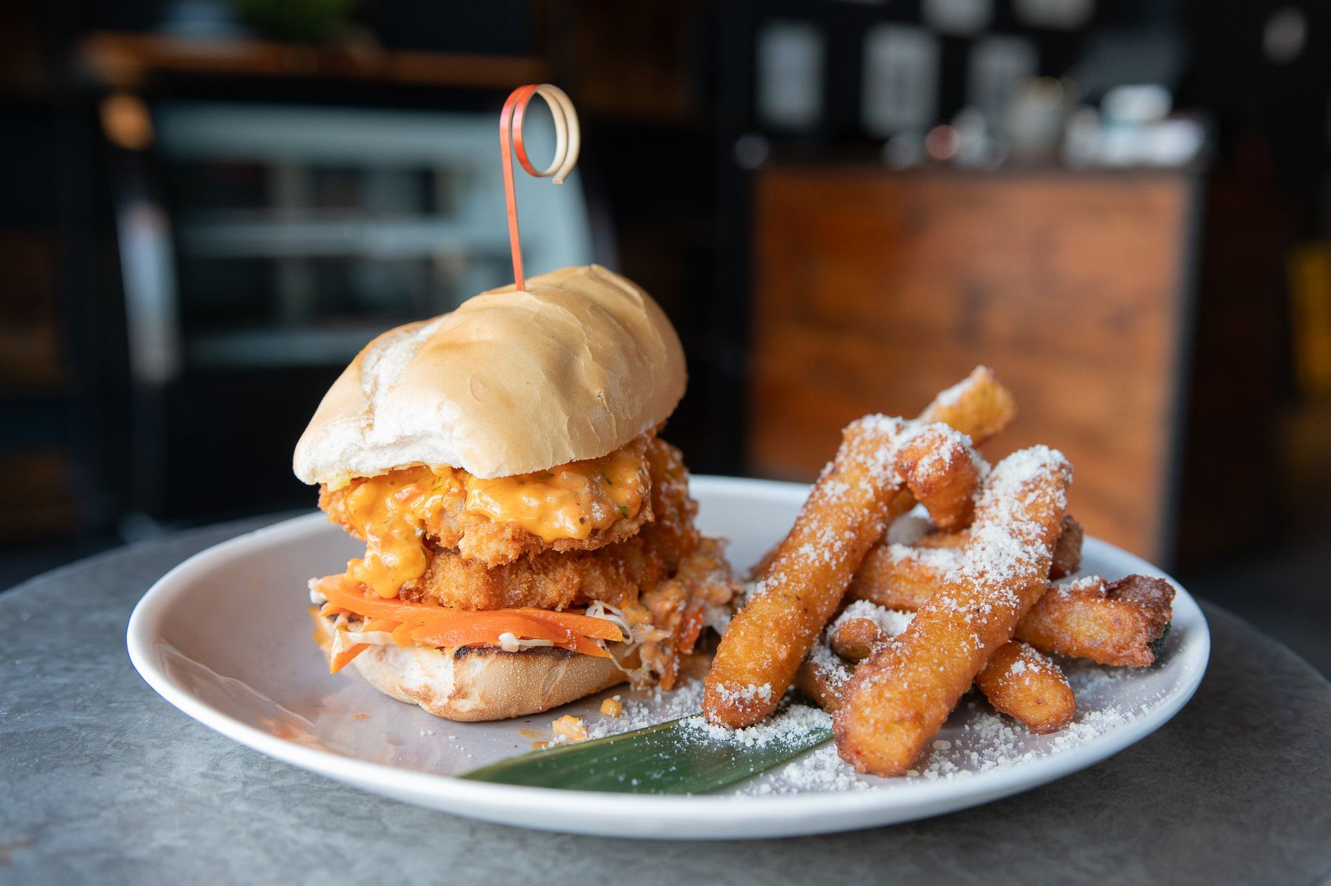 A sandwich and French fries on a white plate on a table.
