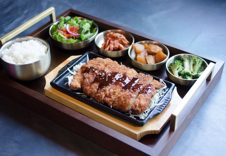 A wooden tray filled with fried food and vegetables.