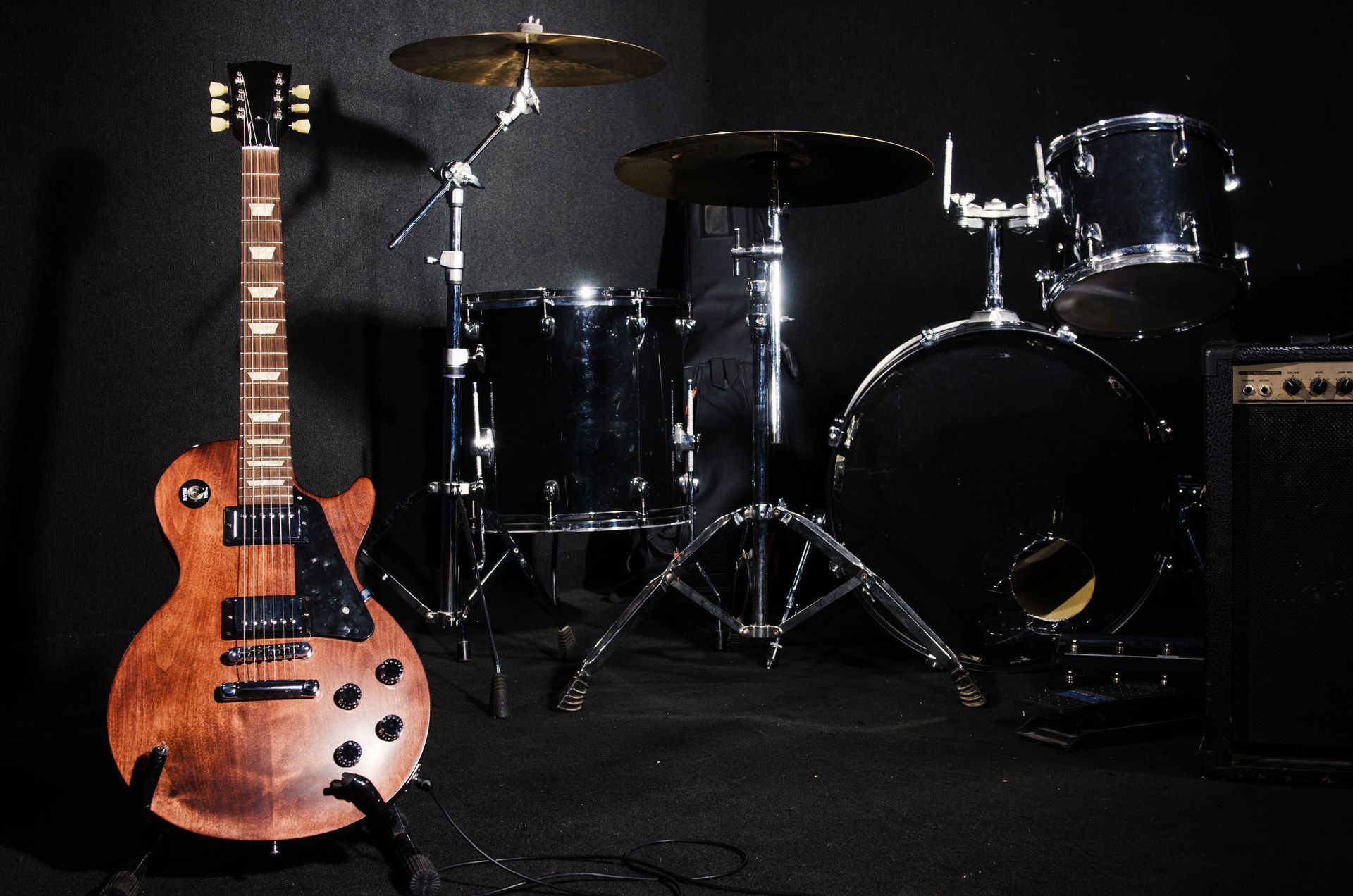 Electric guitar and drum set on a black background.