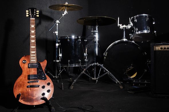 Electric guitar and drum set on a black background.