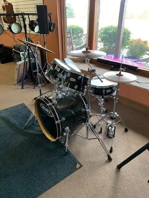 Black Mapex drum set near a window. Cymbals, snare, and tom-toms are visible.