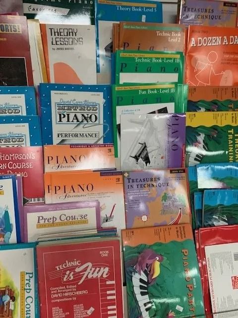 Pile of colorful piano lesson books with titles visible.