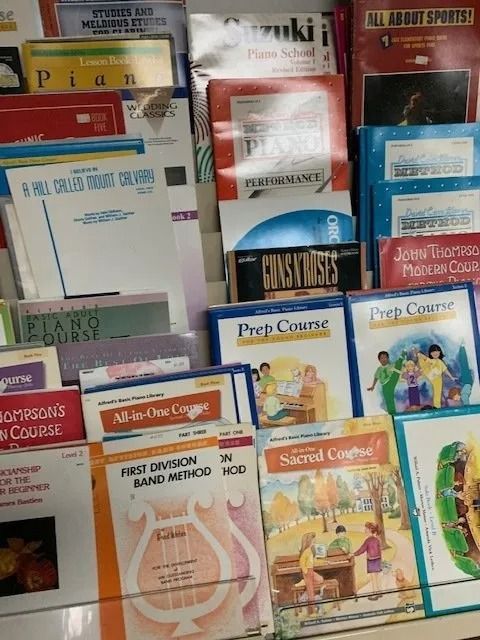 Shelves filled with various music books, including piano and band methods, displayed in a store setting.