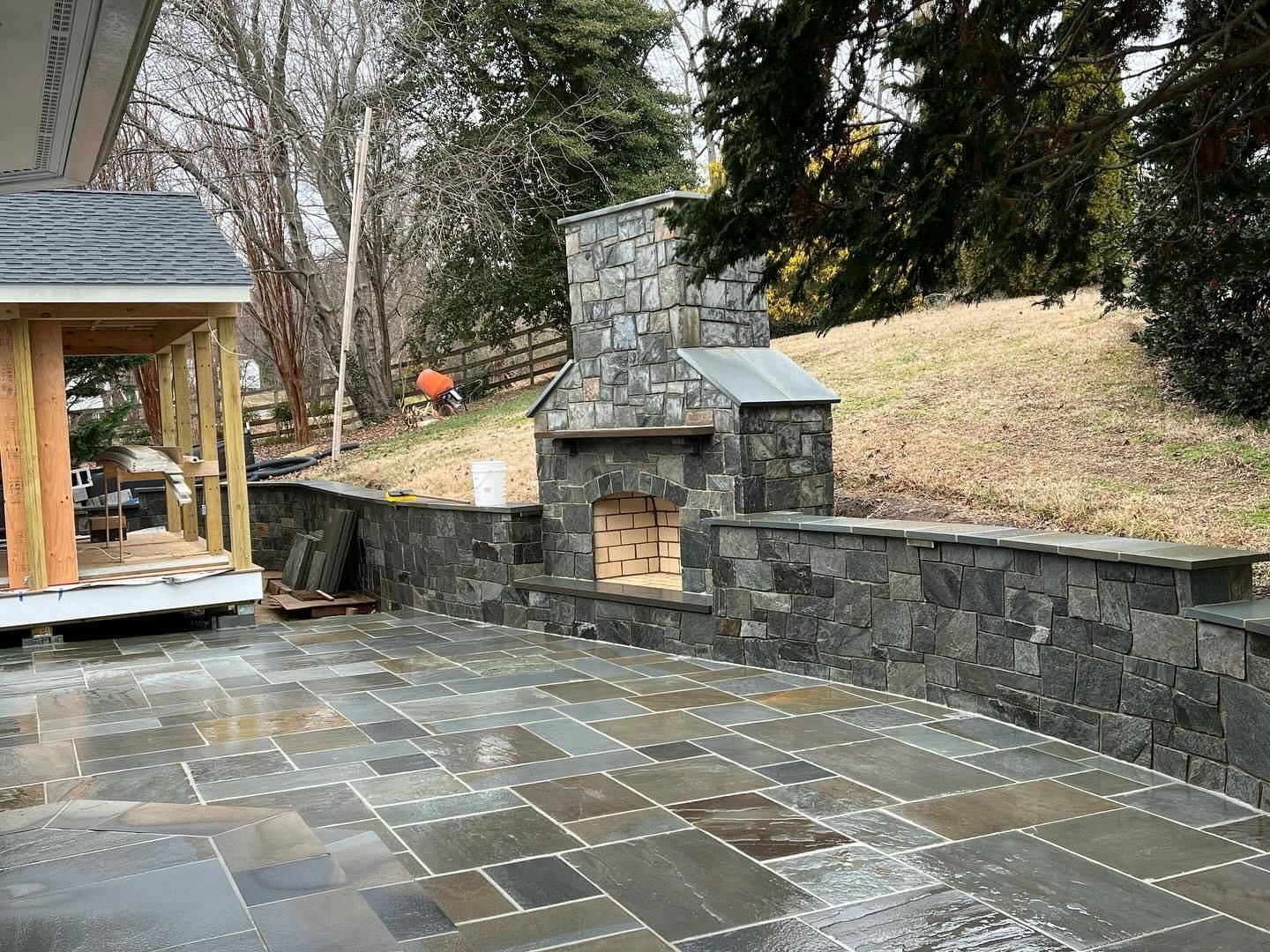 a patio with a stone fireplace and a stone wall .
