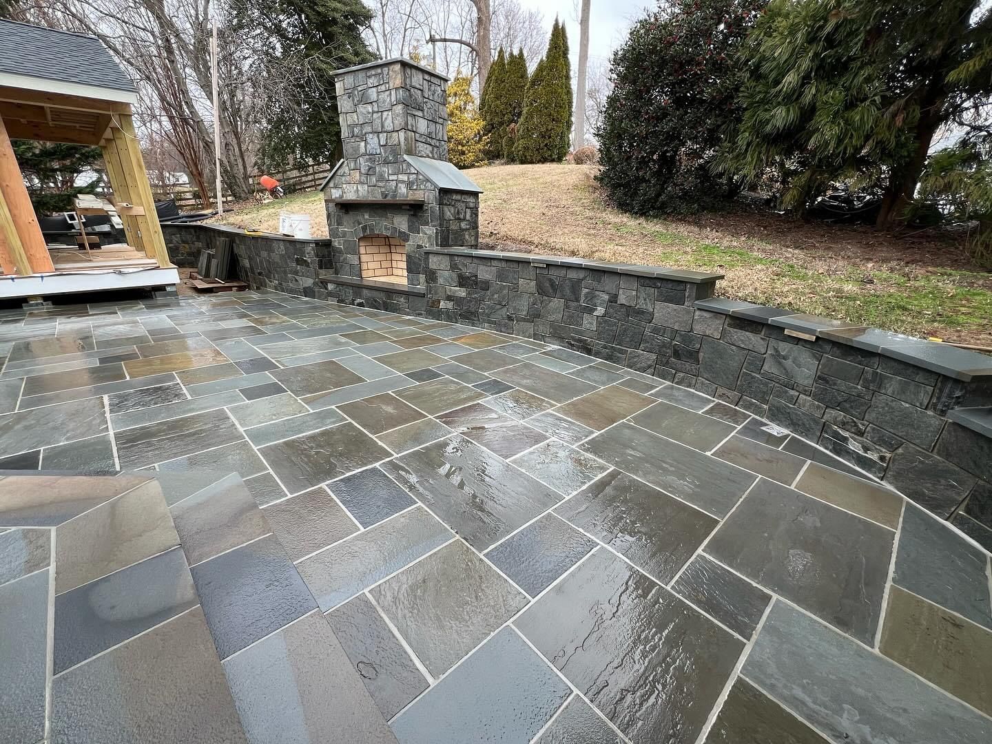 a stone patio with a fireplace in the backyard .