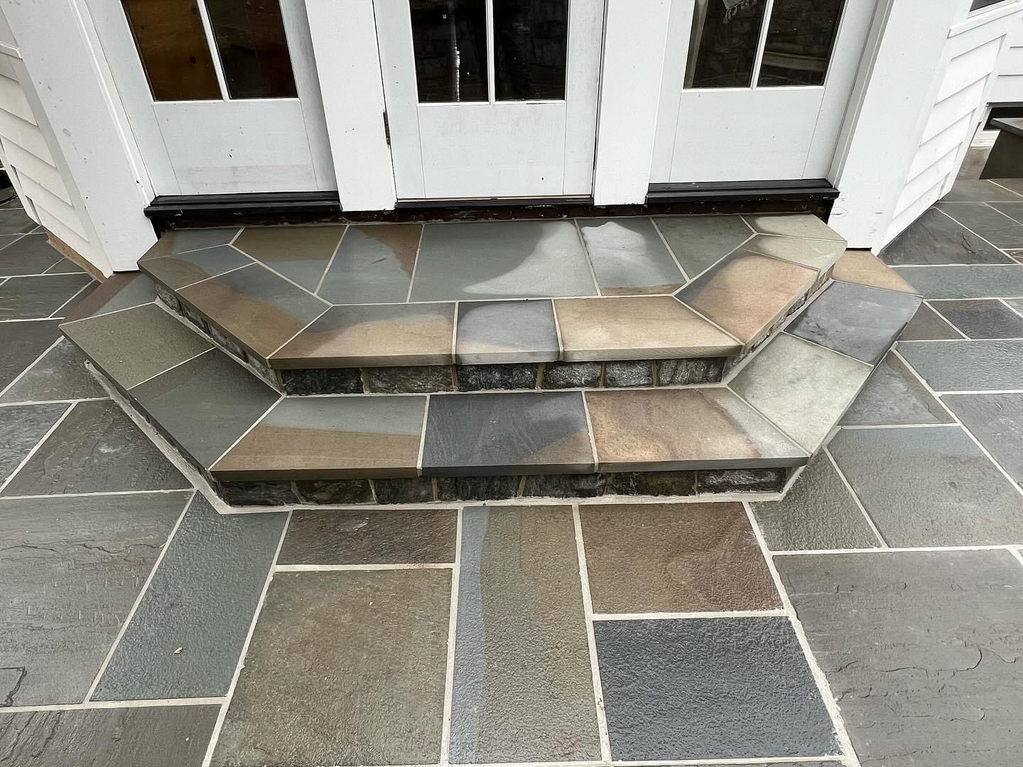 a stone walkway with steps leading to a white door