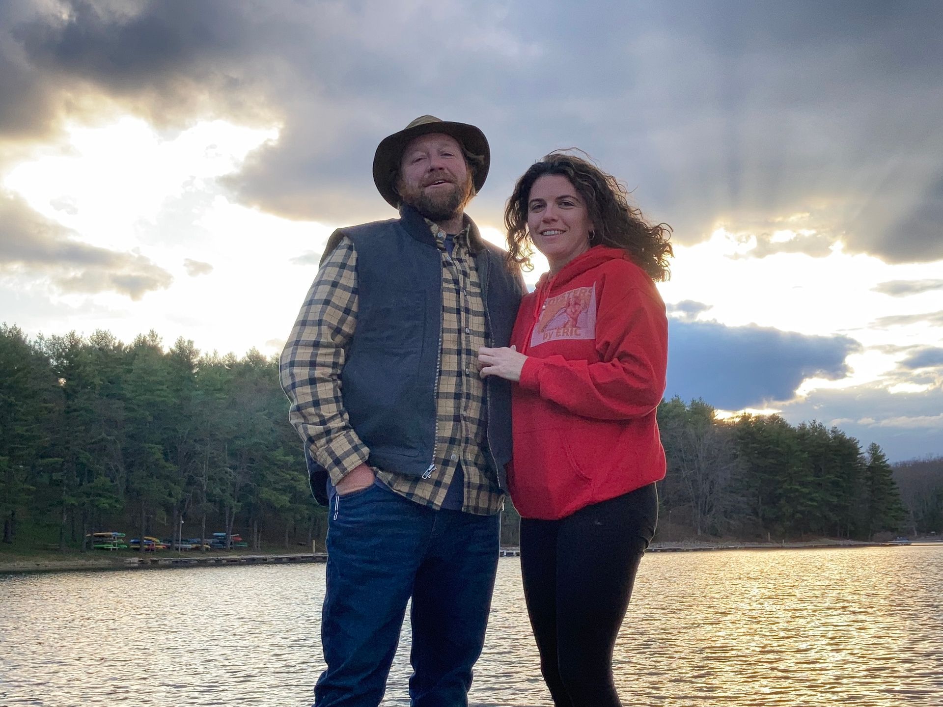 a man and a woman are standing next to each other in front of a lake .