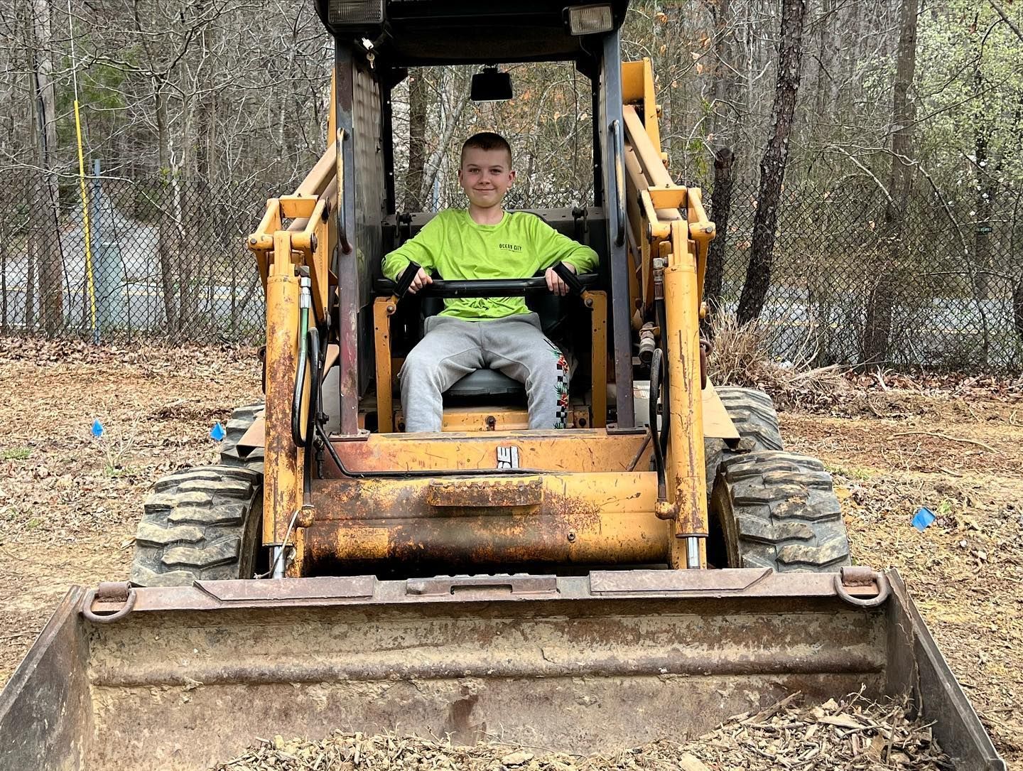 a young boy is sitting in a skidloader.