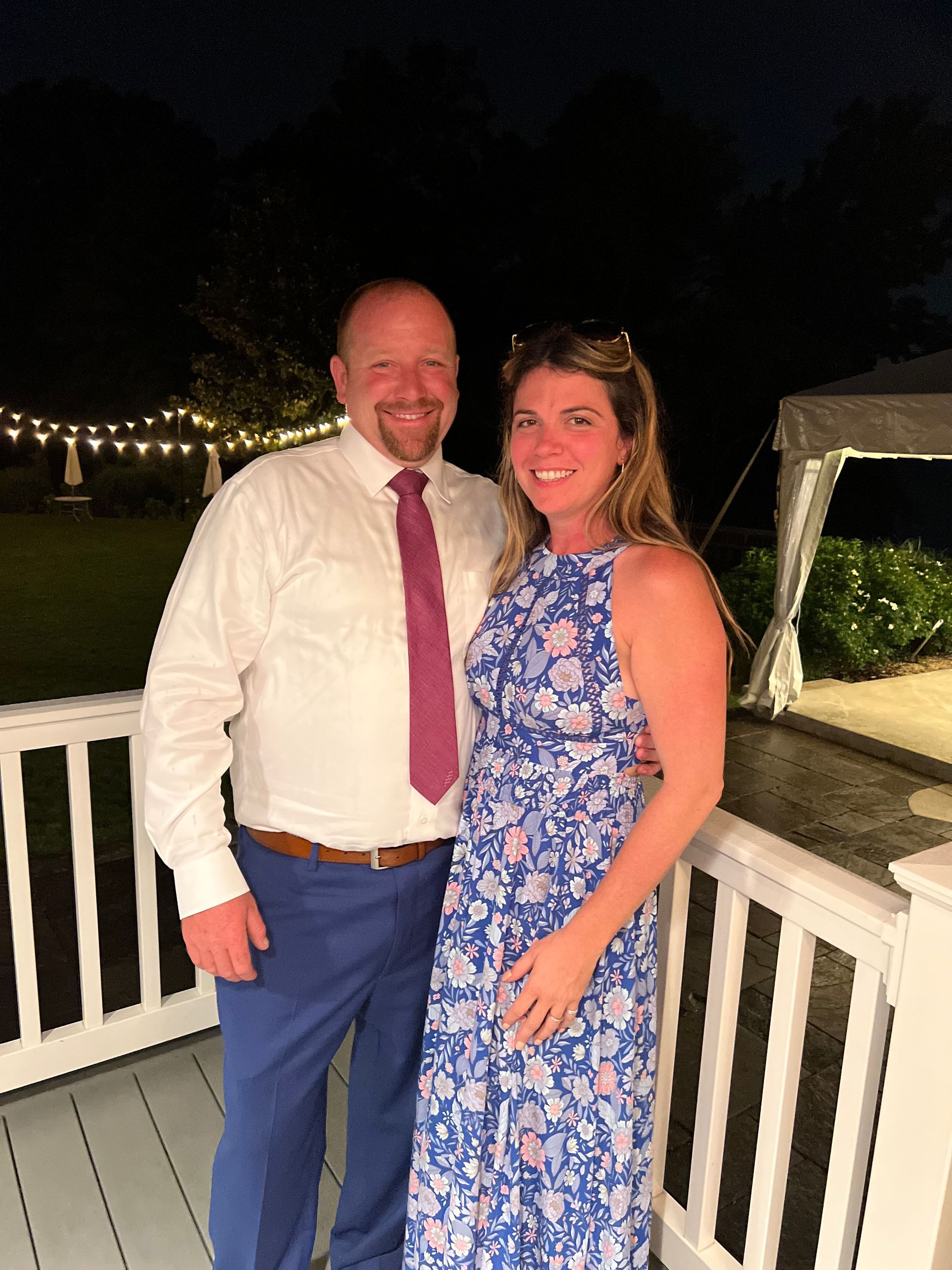 a man and a woman are posing for a picture on a porch at night .