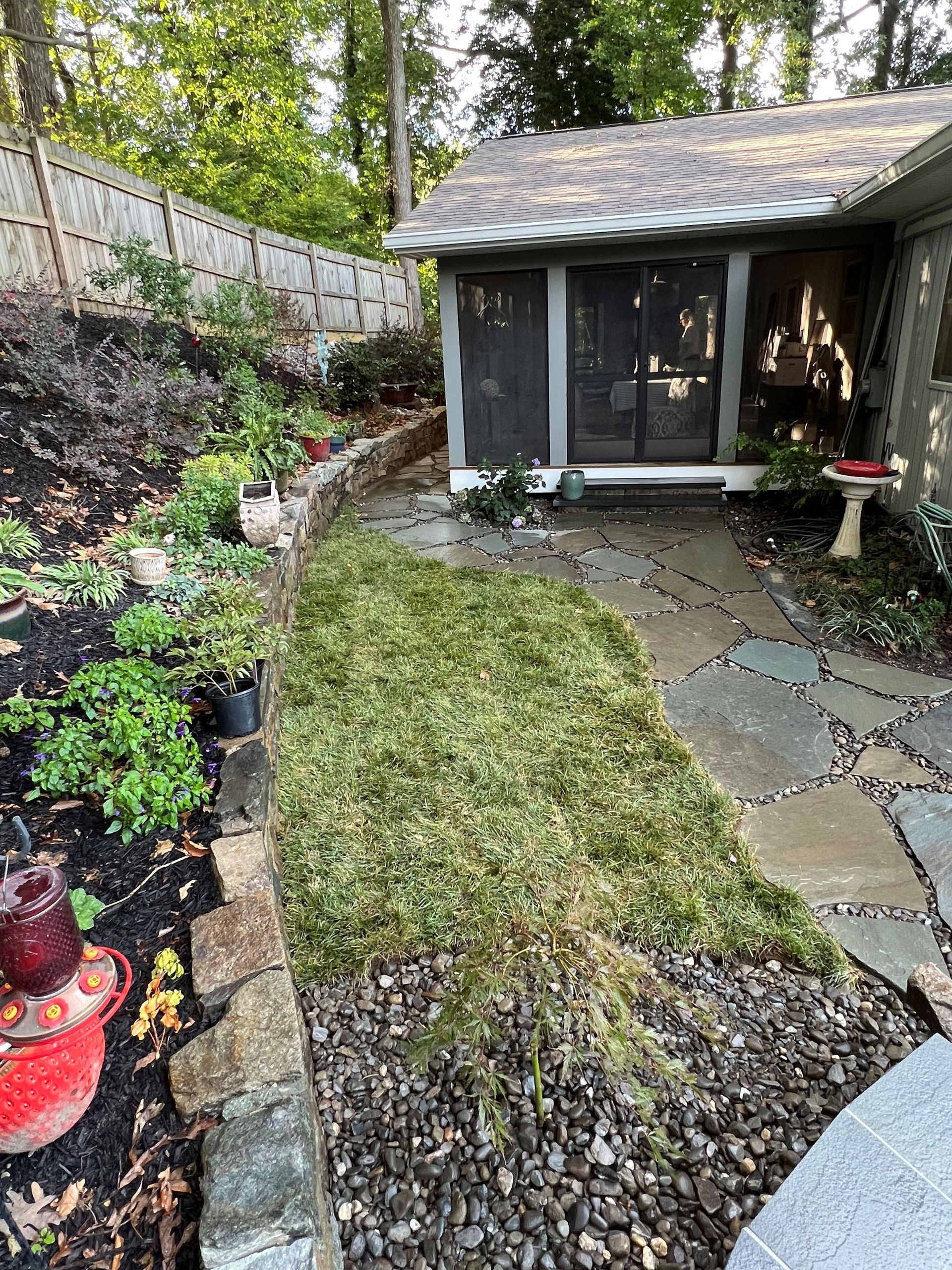 a house with a screened in porch and a lawn in front of it .