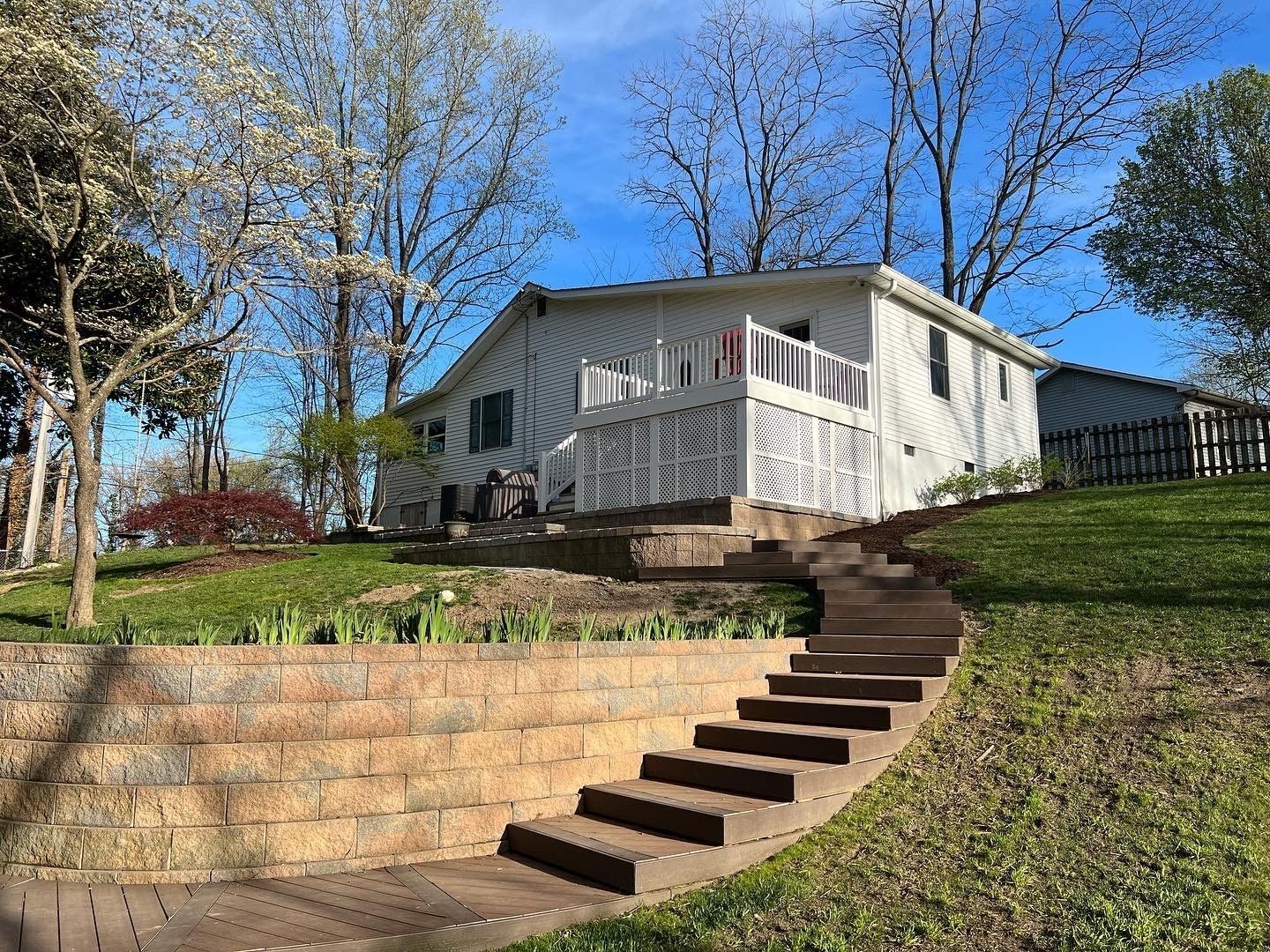 a white house with a deck and stairs leading up to it .