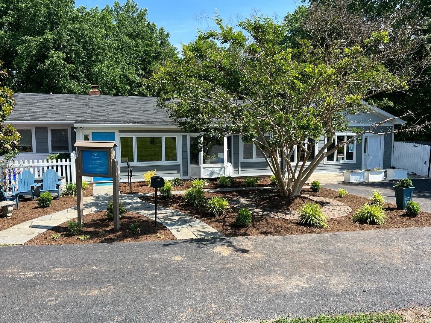 a house with a blue door and a white picket fence is surrounded by trees .