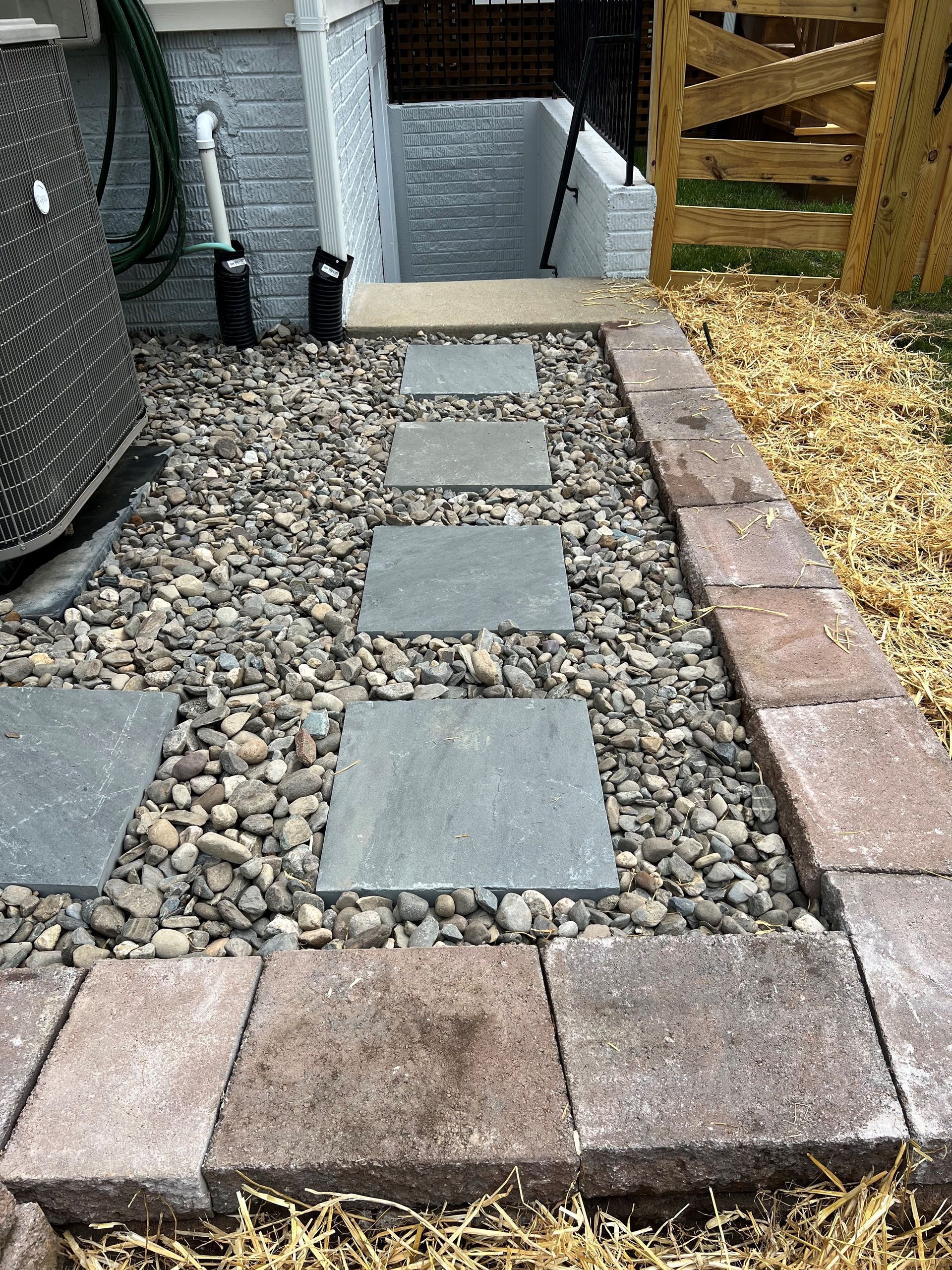 a walkway made of bricks and gravel next to a house .
