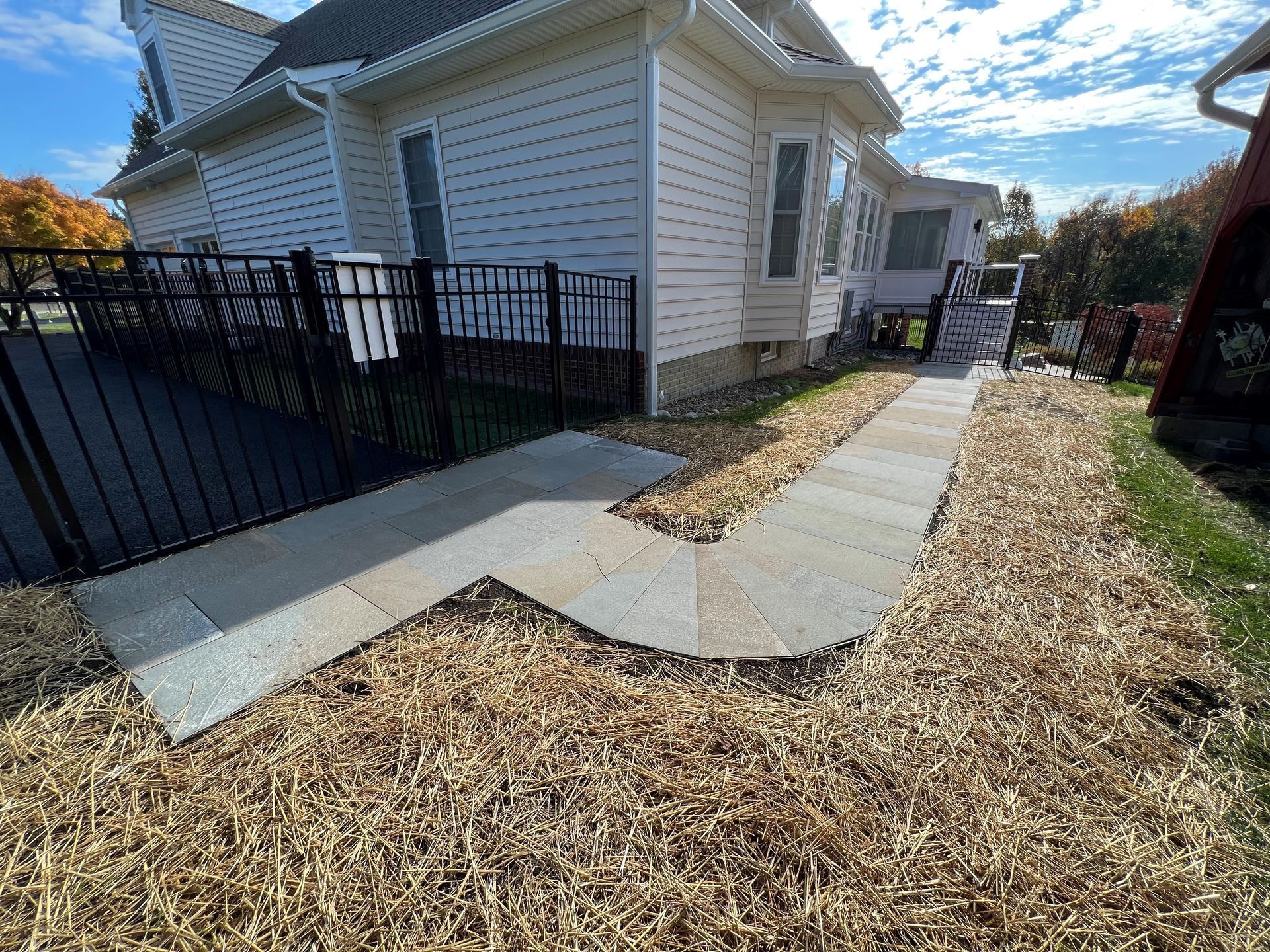 a white house with a black fence and a sidewalk in front of it .