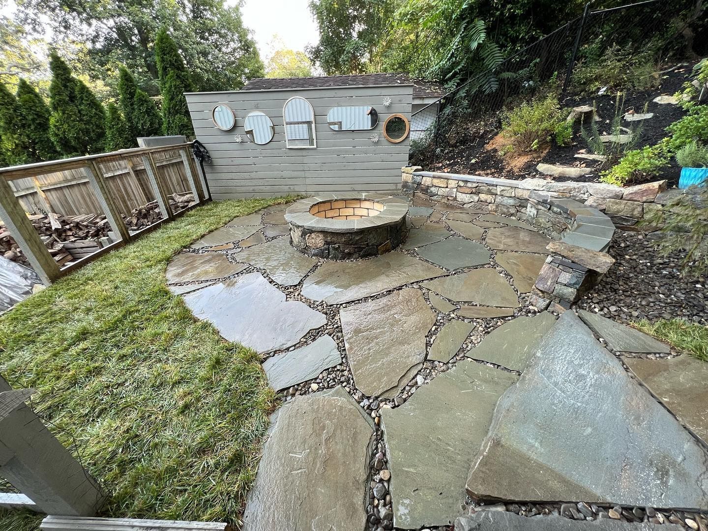 a stone patio with a fire pit in the middle of it .