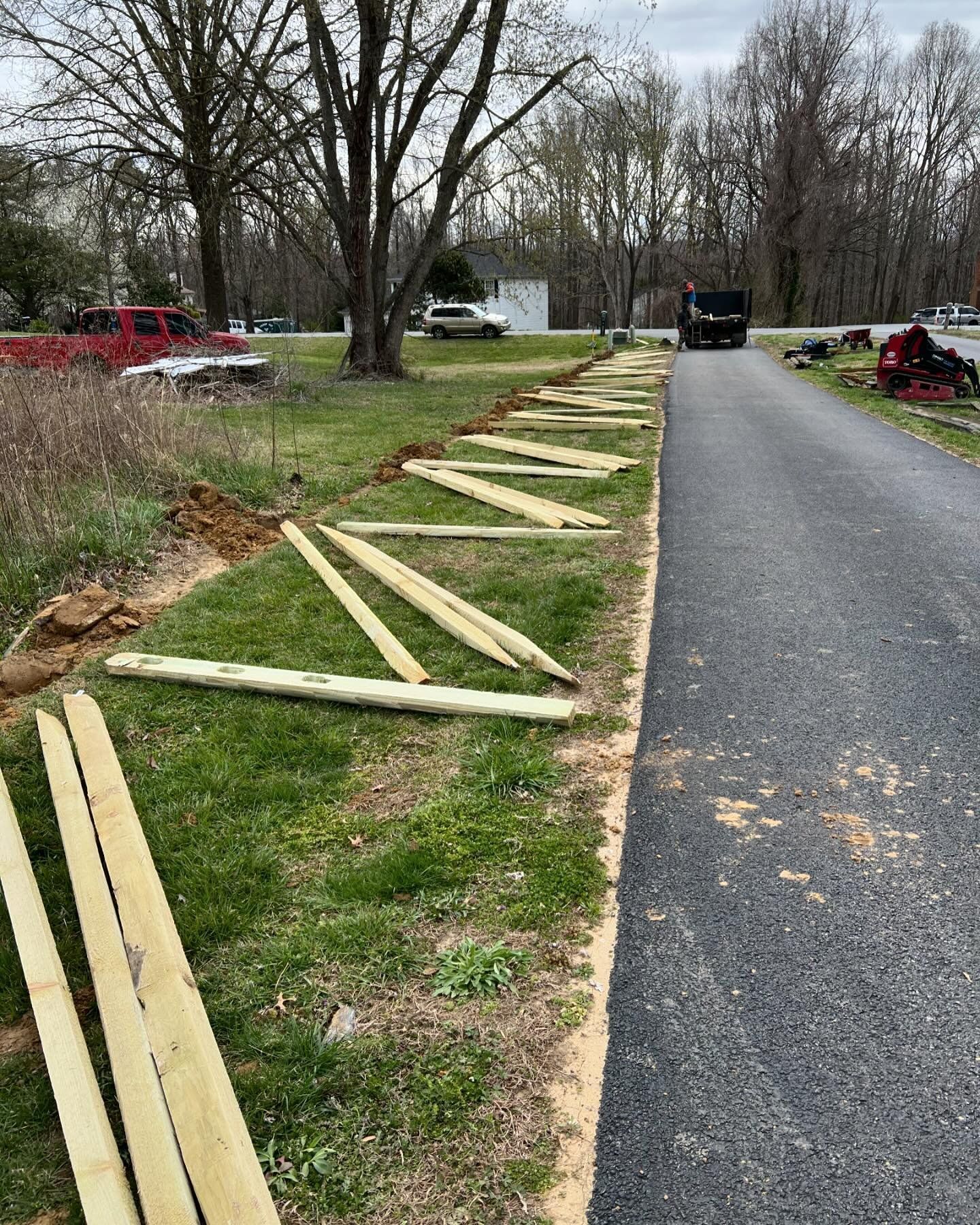 A wooden fence is being built next to a road