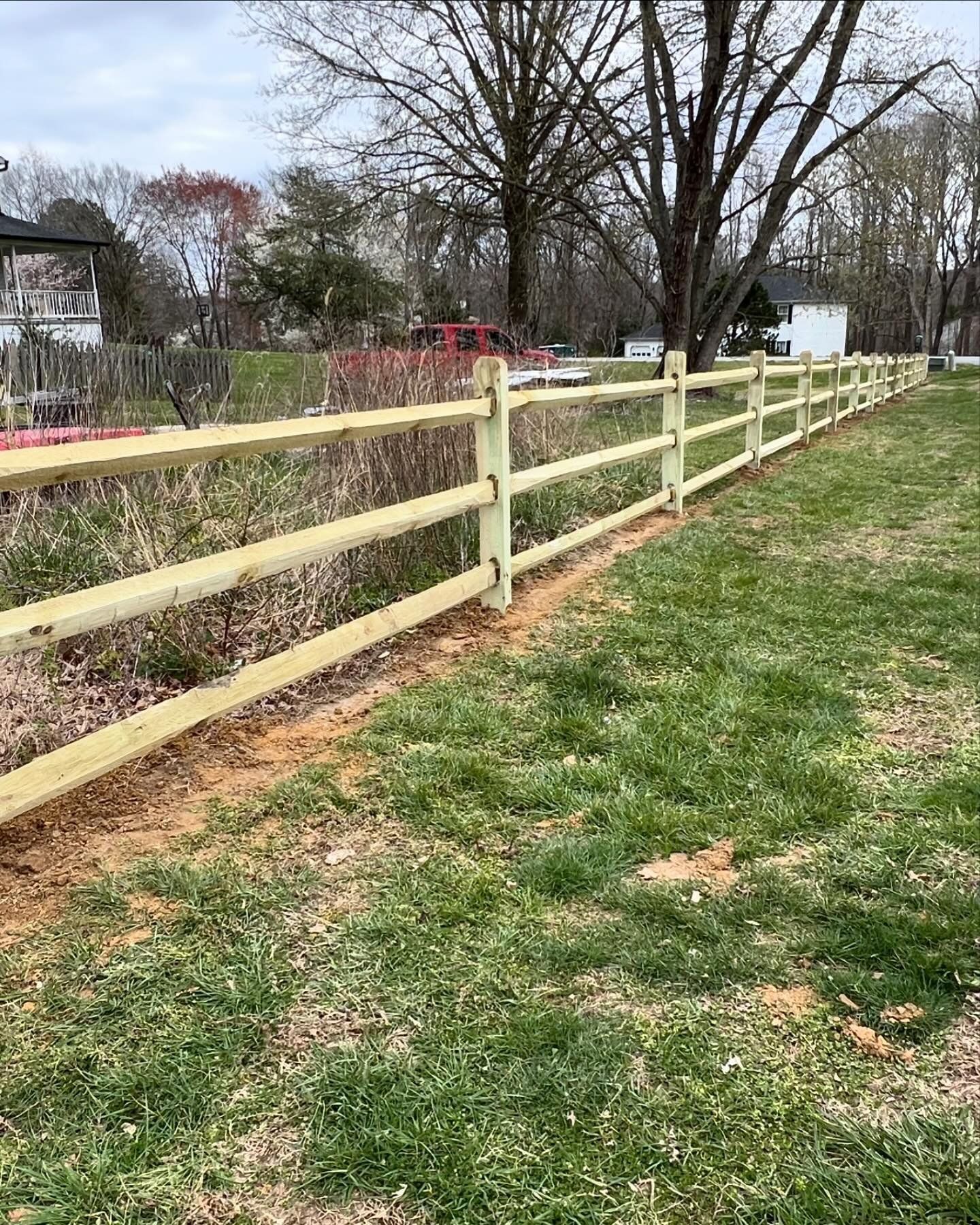 A wooden fence is in the middle of a grassy field