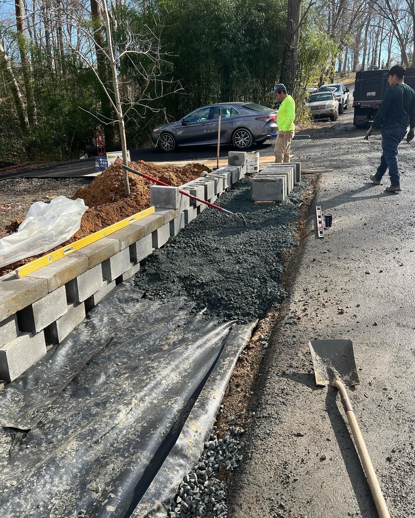 A man is standing next to a pile of gravel on the side of a road