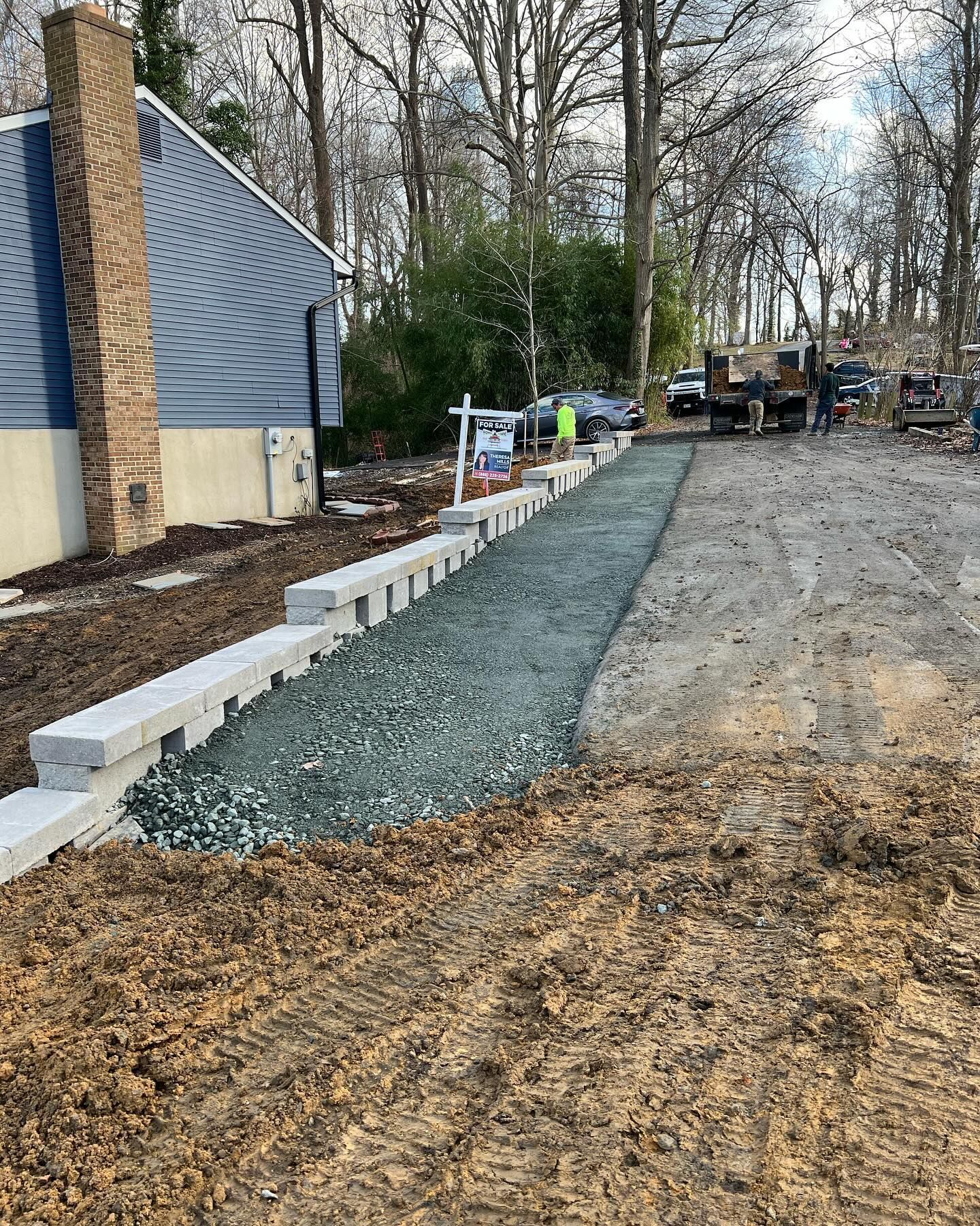 A concrete walkway is being built in front of a house