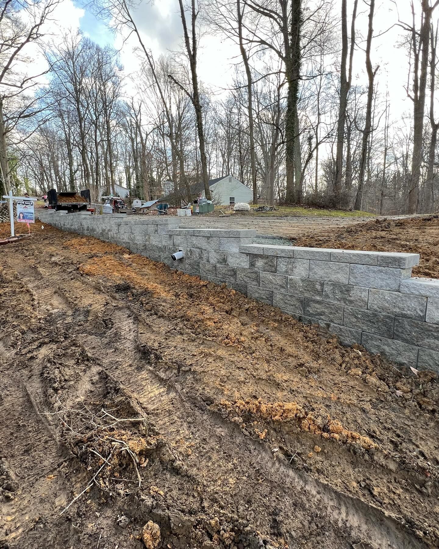 A brick wall is being built on the side of a dirt road