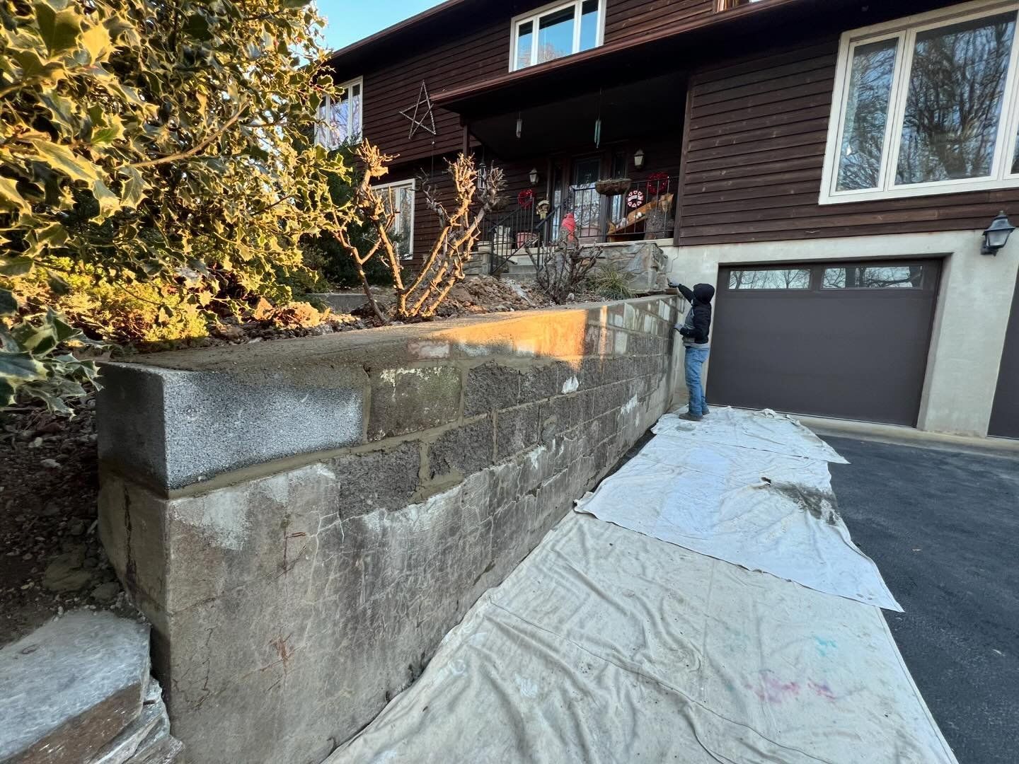 A man is standing next to a brick wall in front of a house