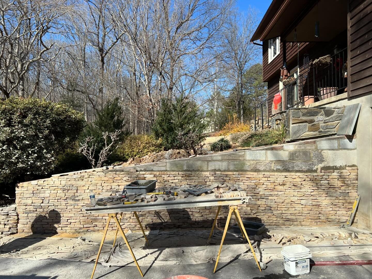 A wooden table is sitting in front of a stone wall