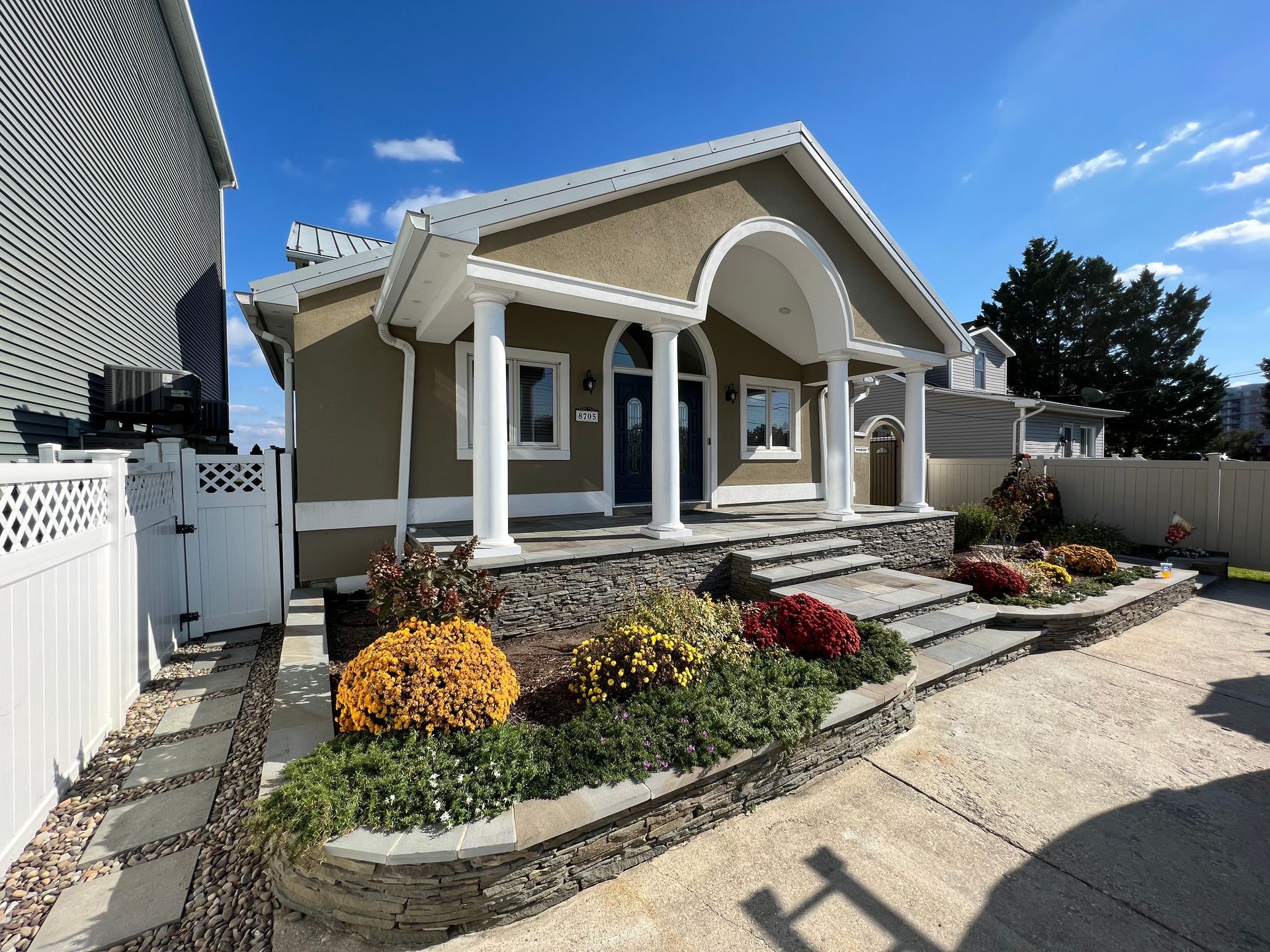 a house with a white fence and flowers in front of it