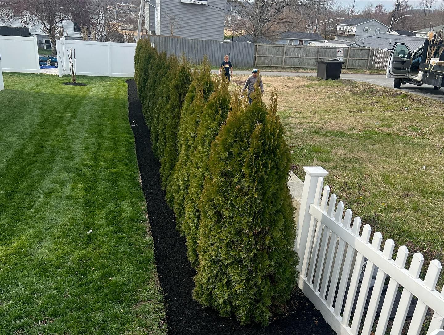 a white picket fence surrounds a lush green yard .