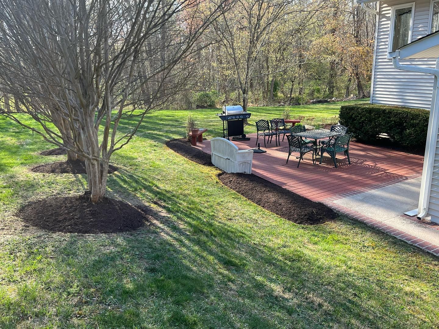 there is a patio with a grill and chairs in the backyard of a house .