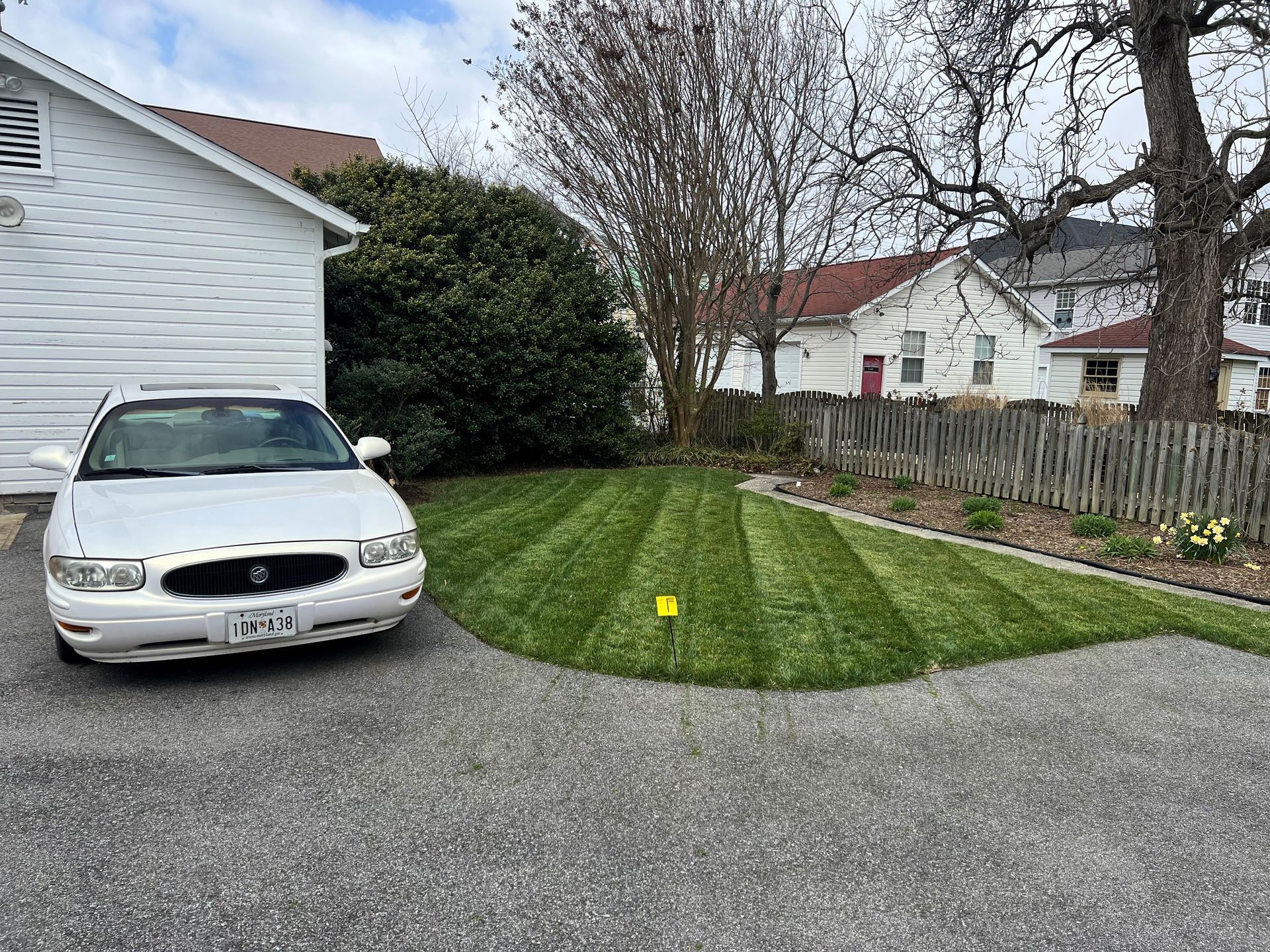 a white car is parked in a driveway next to a house .