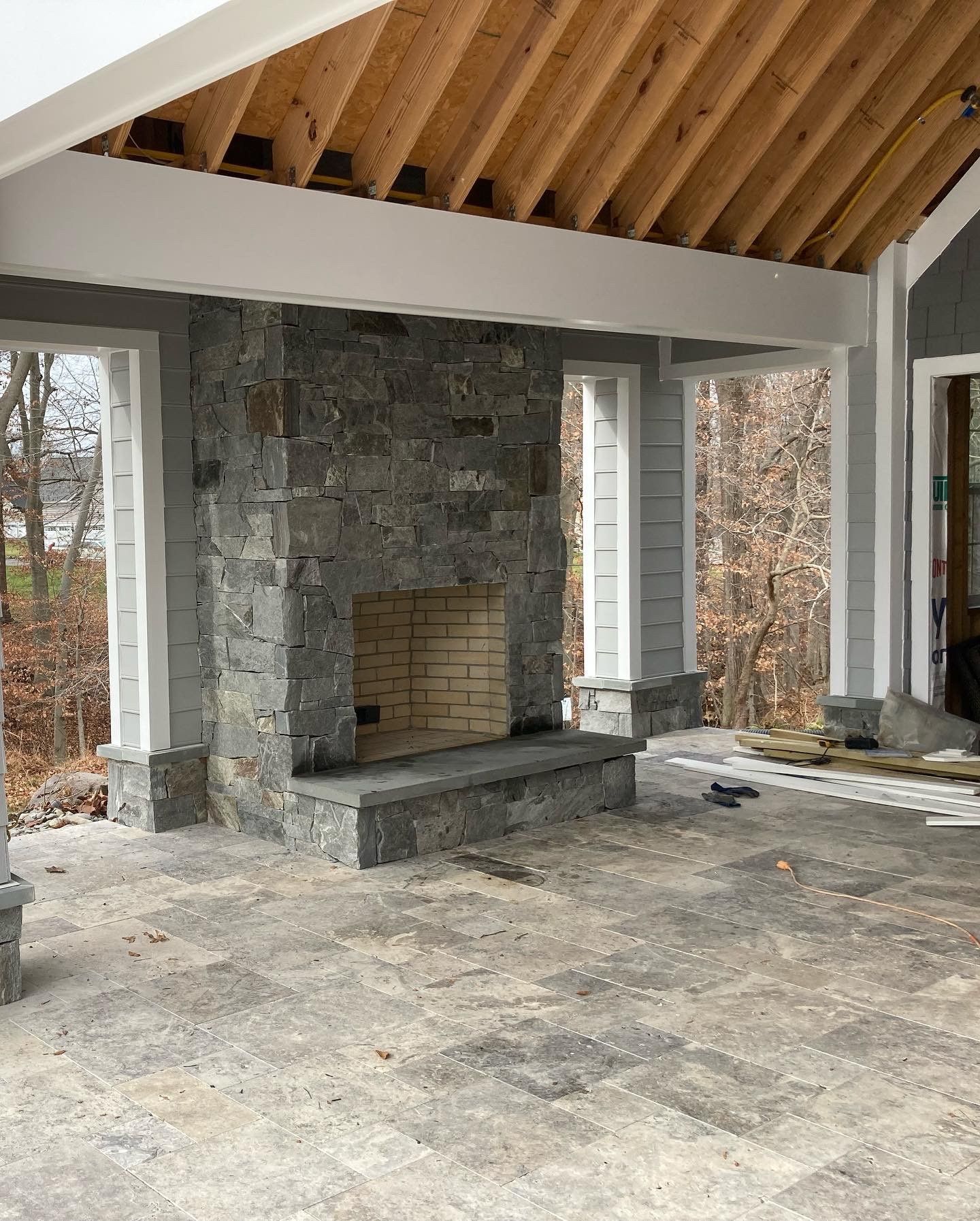 an empty room with a stone fireplace and a wooden ceiling