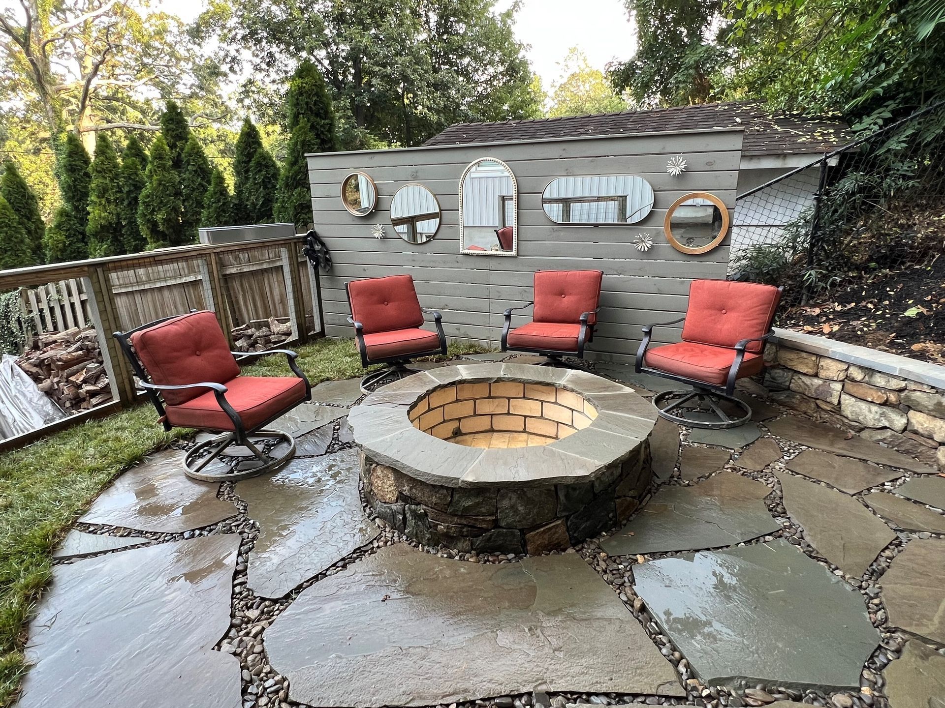 there is a fire pit in the middle of the patio with chairs around it .