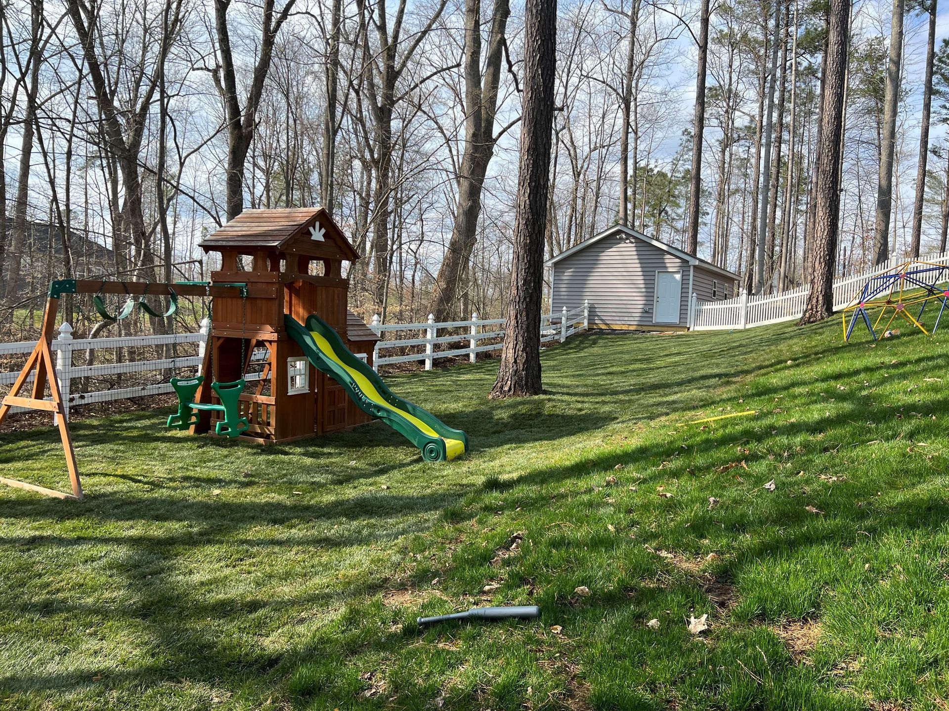 a wooden playground with a slide and swings in a backyard .