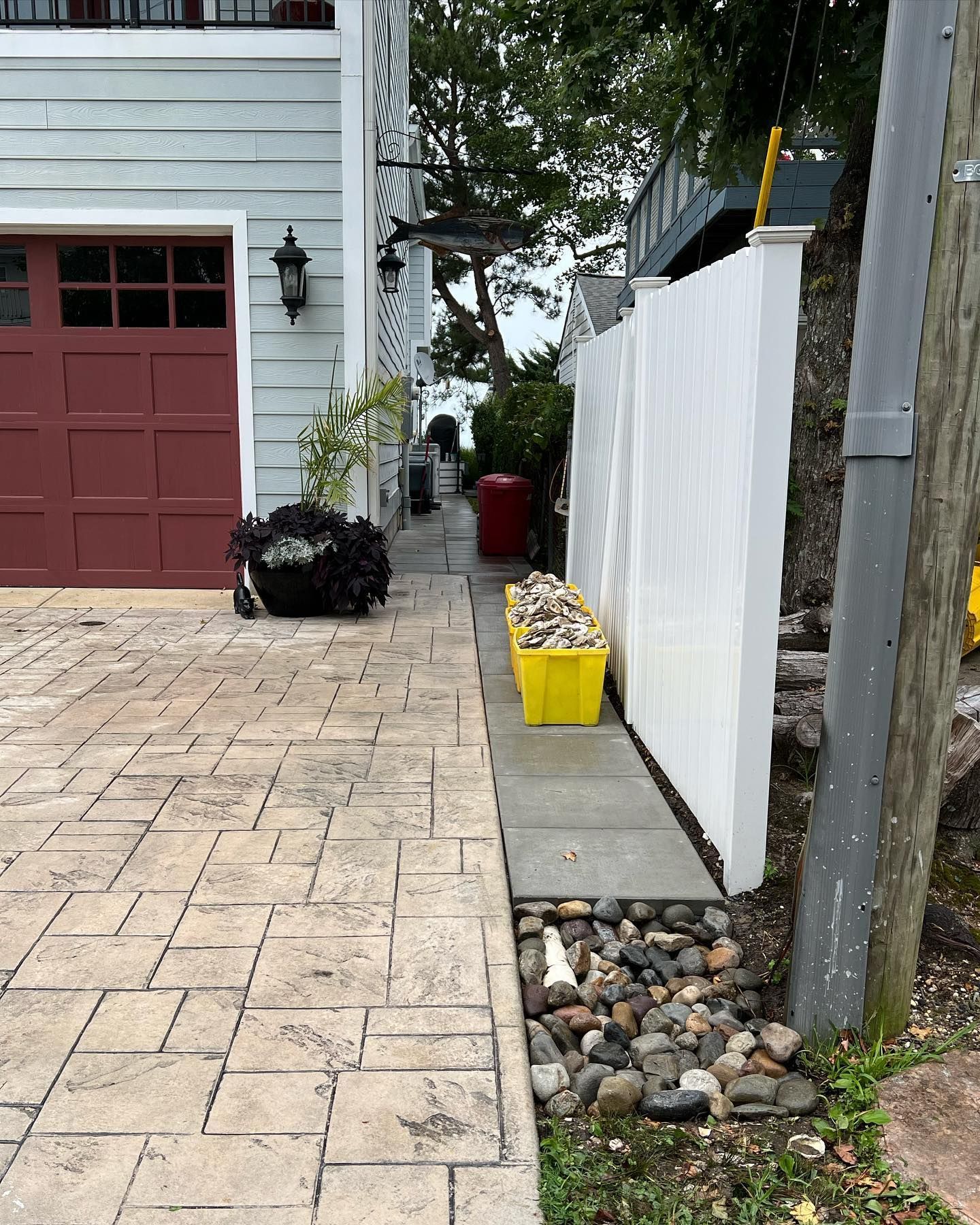 a driveway with a red garage door and a white fence