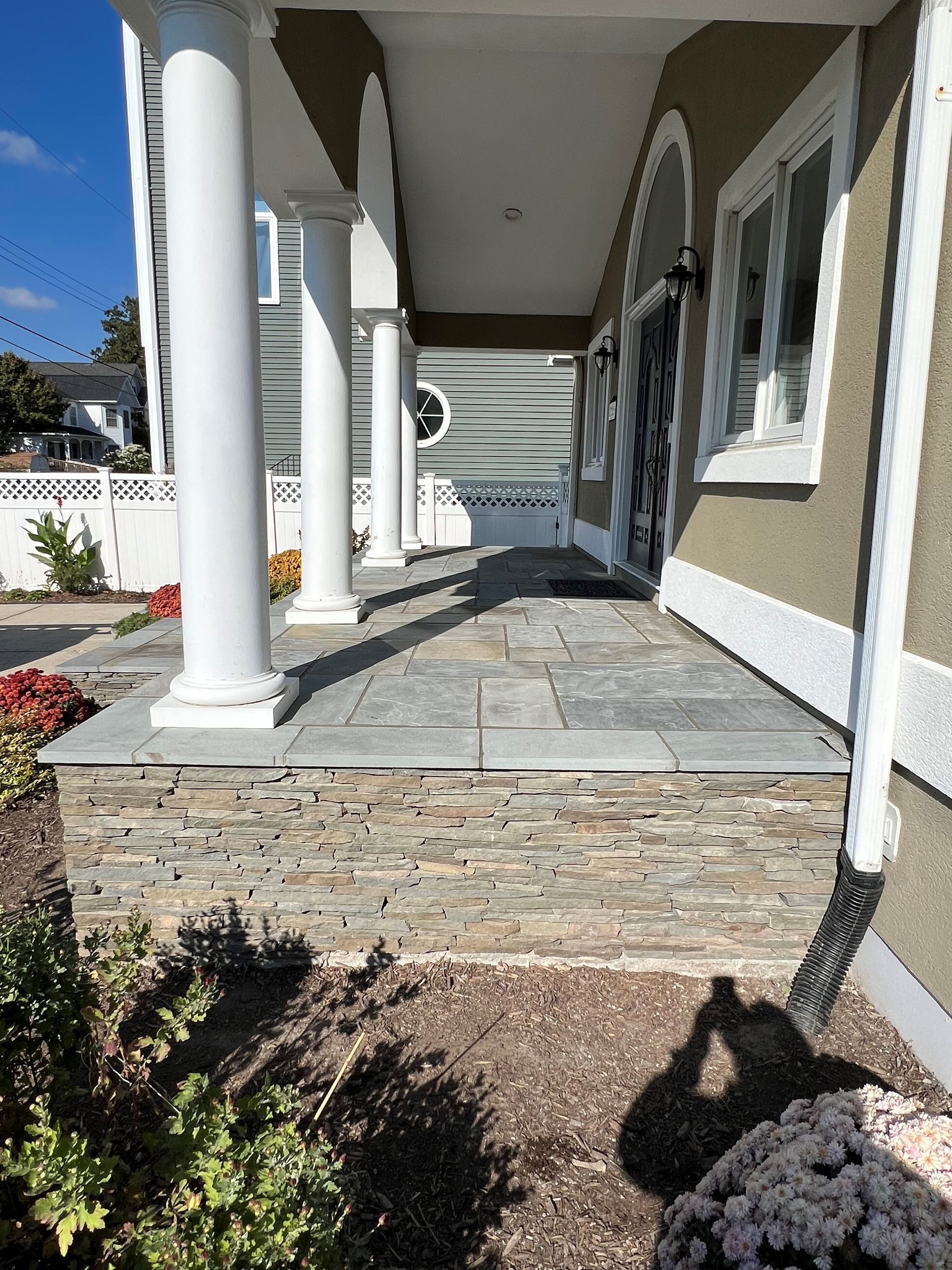 a porch with columns and a stone walkway leading to the front door of a house .
