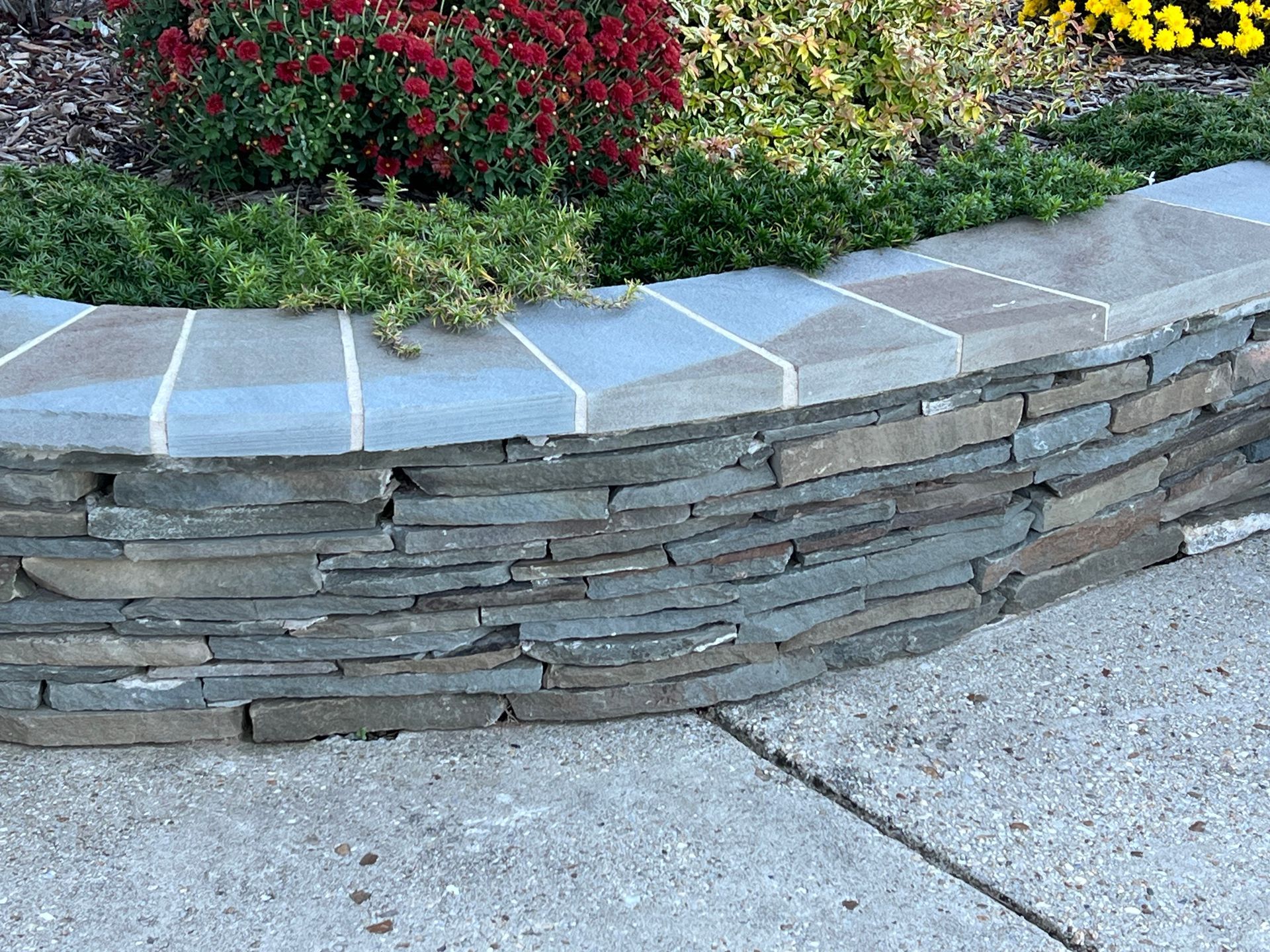 a stone wall with a flower bed in the middle of it