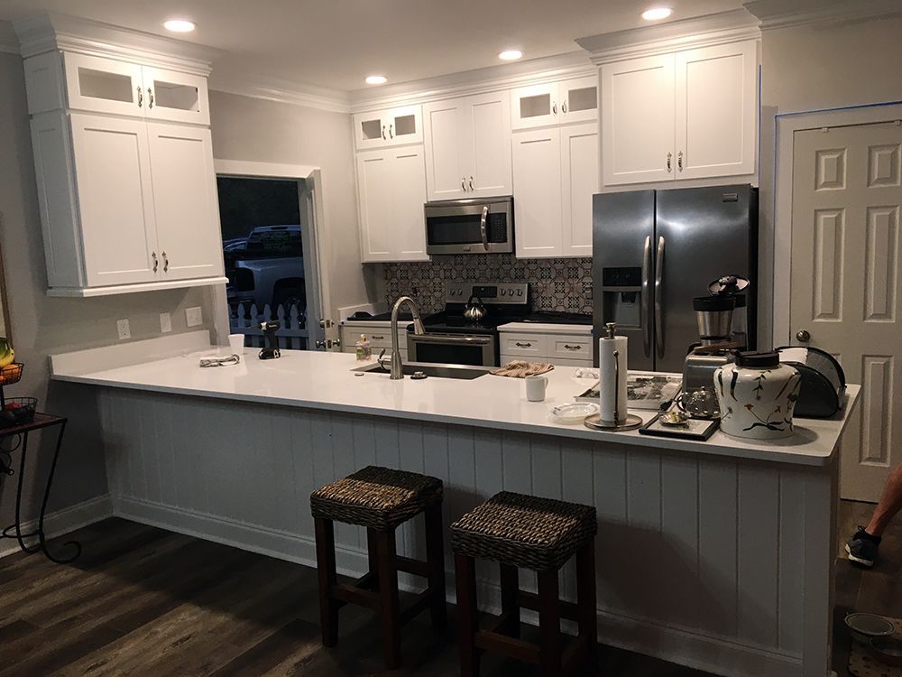 A kitchen with white cabinets , stainless steel appliances , and a large island.