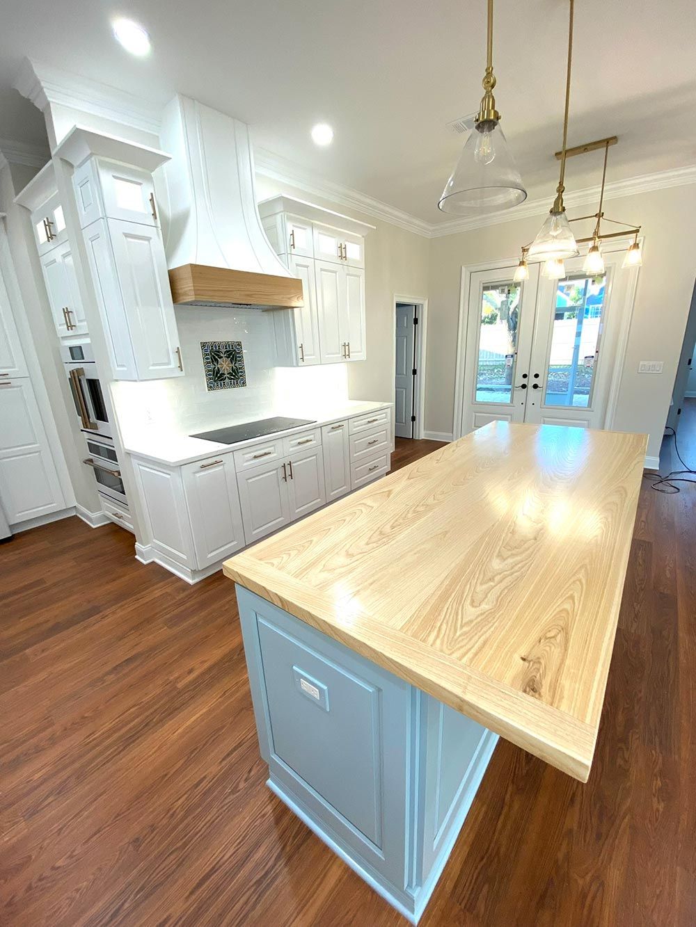 Light blue kitchen island with a wood countertop, in a bright kitchen with white cabinets.