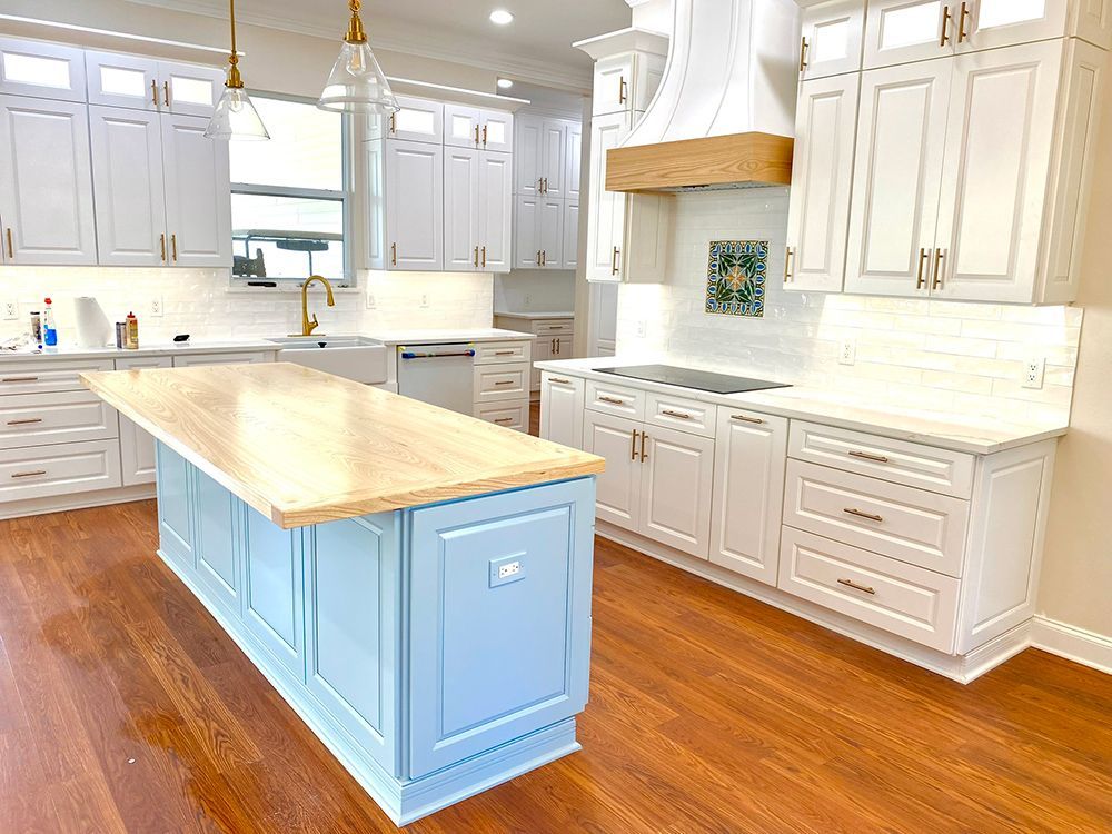 Spacious kitchen with a light blue island, white cabinets, wooden countertops, and hardwood floors.