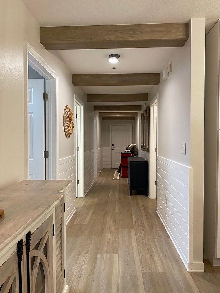 A long hallway with wooden beams and a dresser in the middle of it.