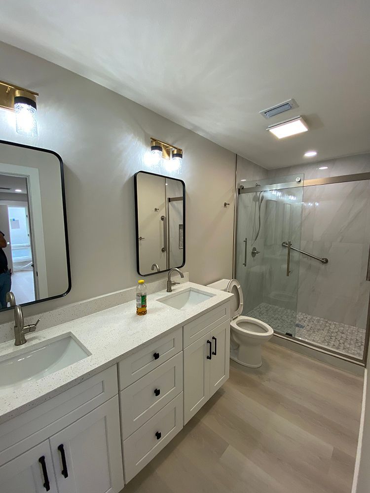 A bathroom with two sinks , a toilet , and a walk in shower.