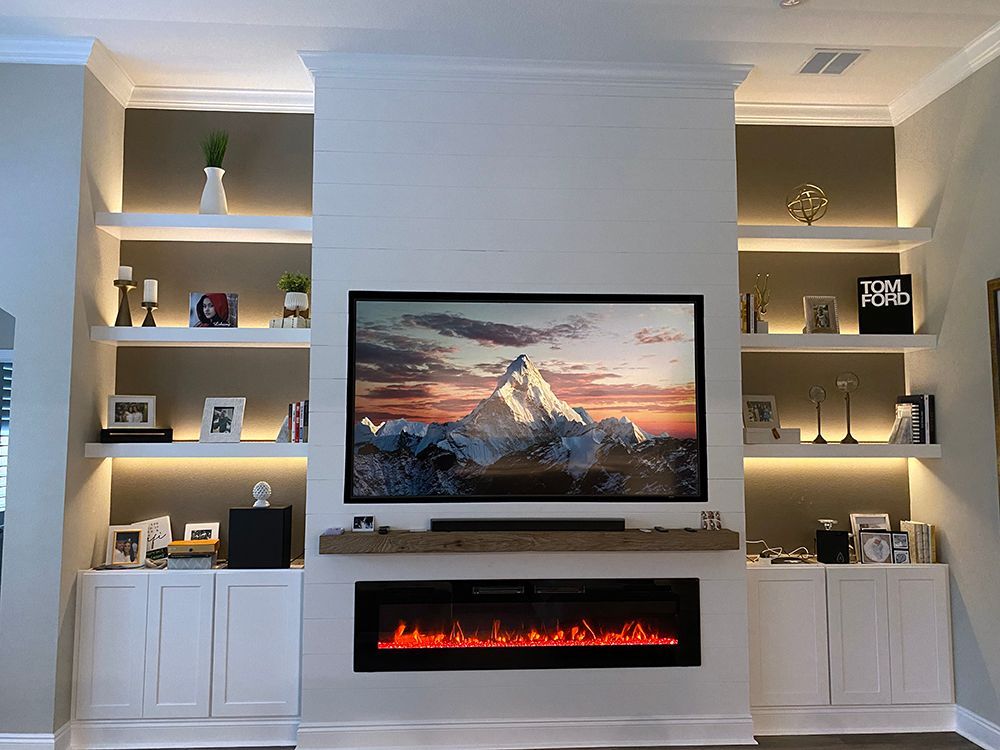 A living room with a fireplace and a flat screen tv on the wall.