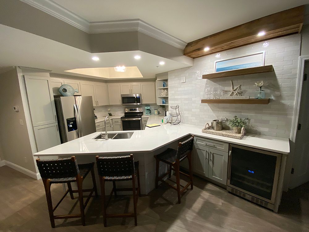 A kitchen with a large island and stools and a refrigerator.