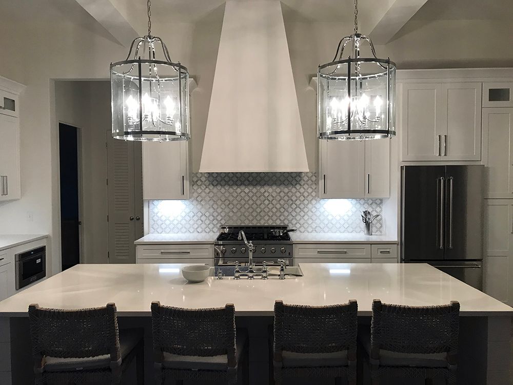 A kitchen with white cabinets , a stove , a refrigerator , and a large island.