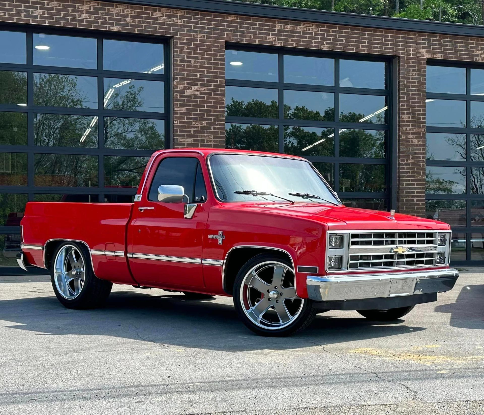 A red truck is parked in front of a brick building